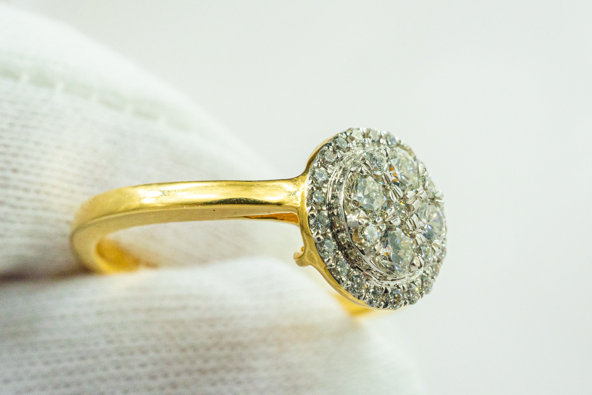 Side view of 18K gold oval halo diamond ring showing raised halo head and band