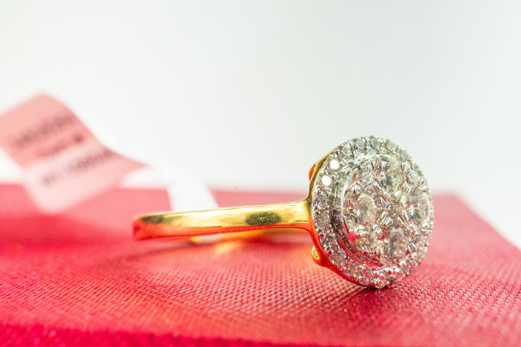 18K gold oval halo diamond ring with 0.29 CTW diamonds shown on red background