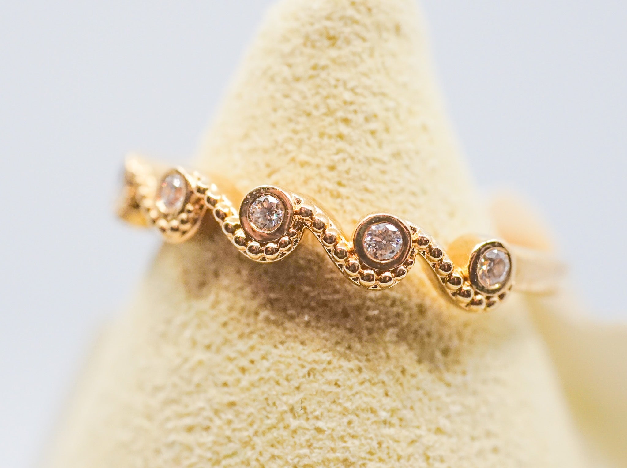18k gold band ring with five bezel-set round diamonds and milgrain detailing on display.