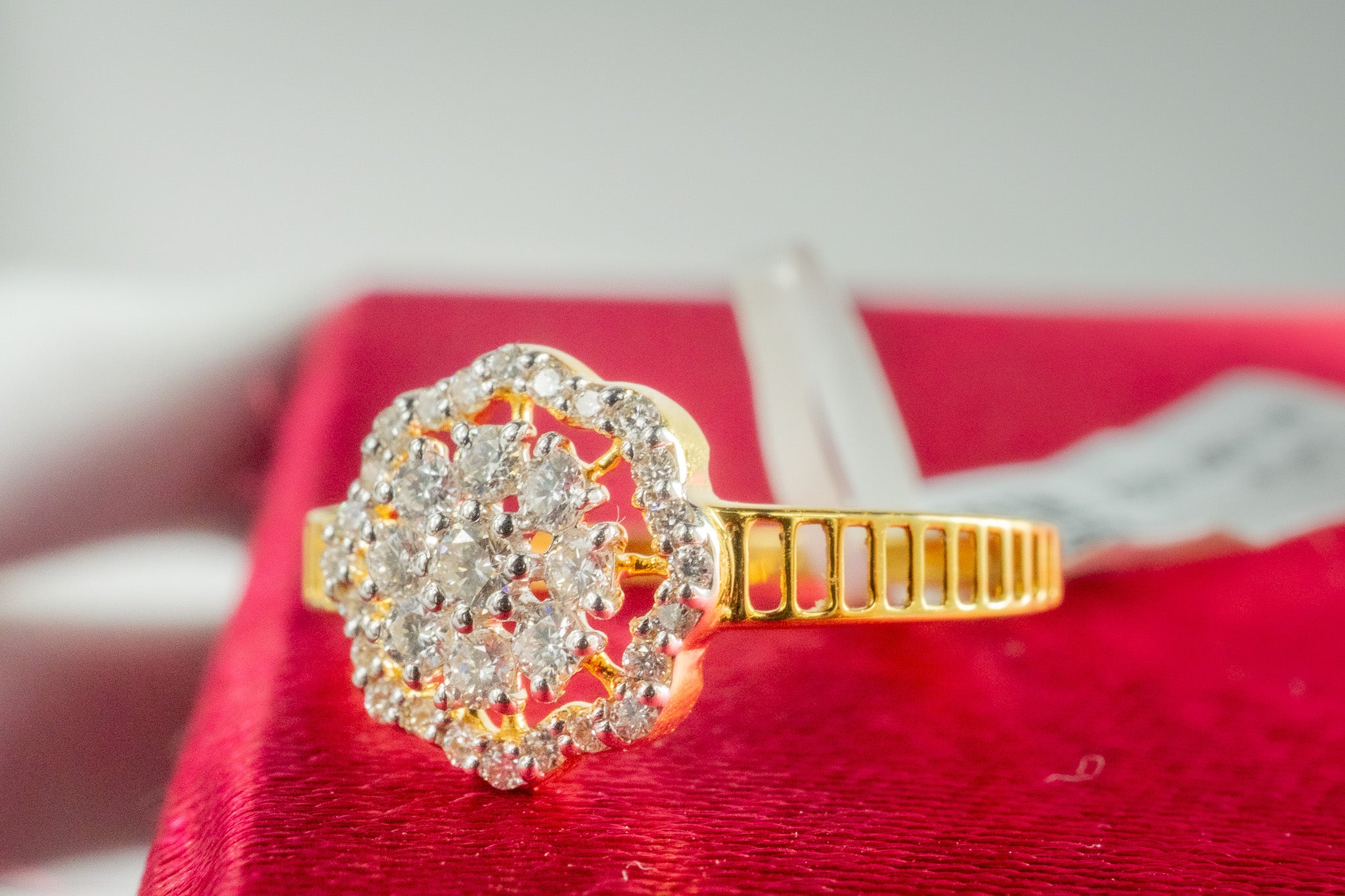 18k yellow gold diamond halo cluster ring with scalloped halo, side view on red jewelry box.