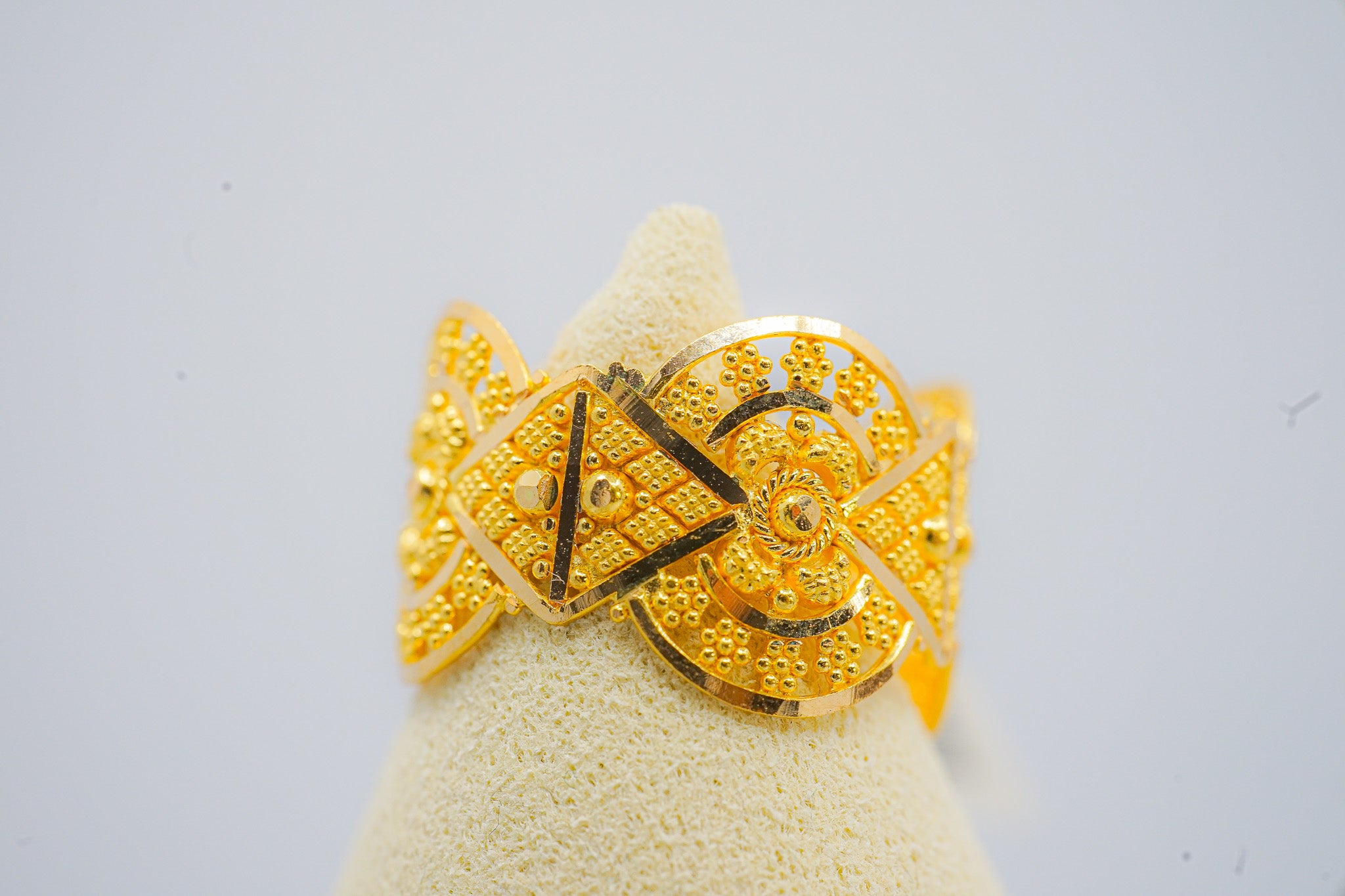 22K gold ring  4.14g in size 6 with ornate geometric textured design on a display cone