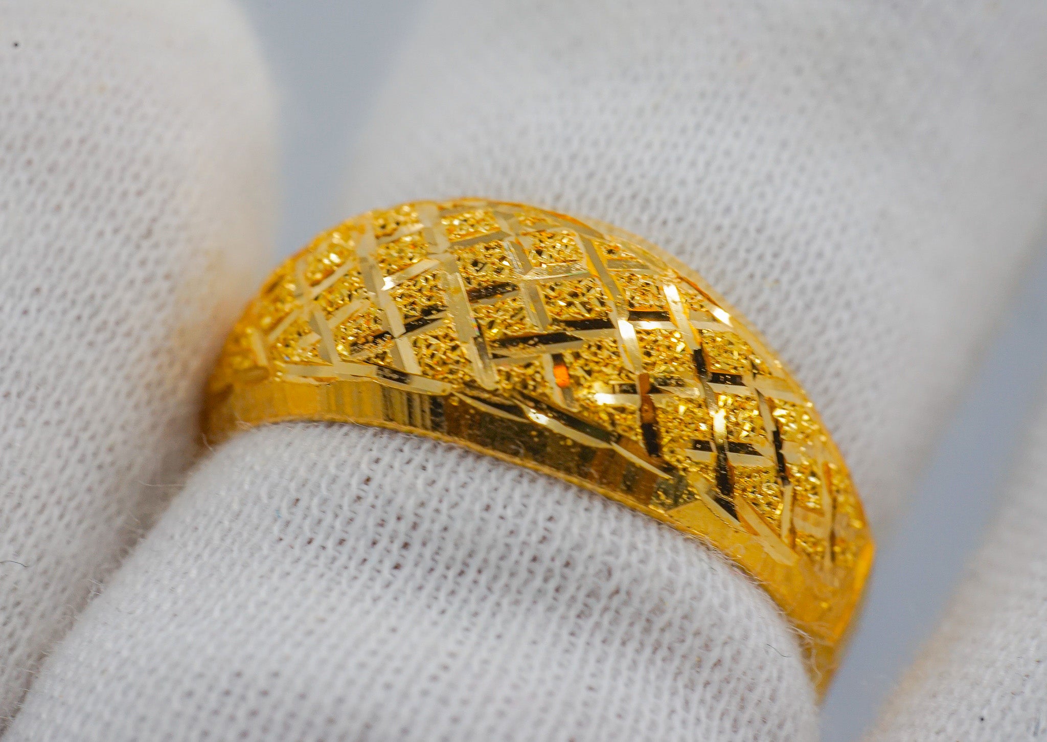 Close-up of the textured lattice pattern on a 22K gold band ring