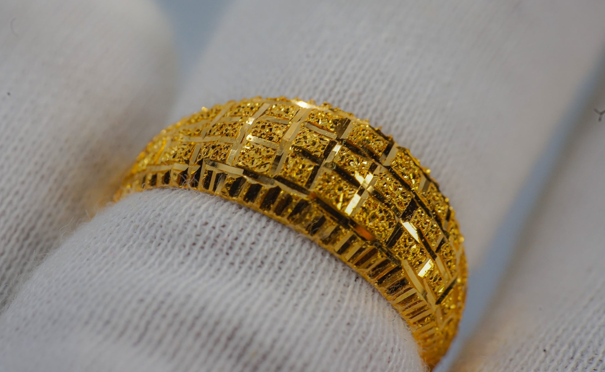 22K gold wide band ring shown on a hand, featuring a textured geometric pattern