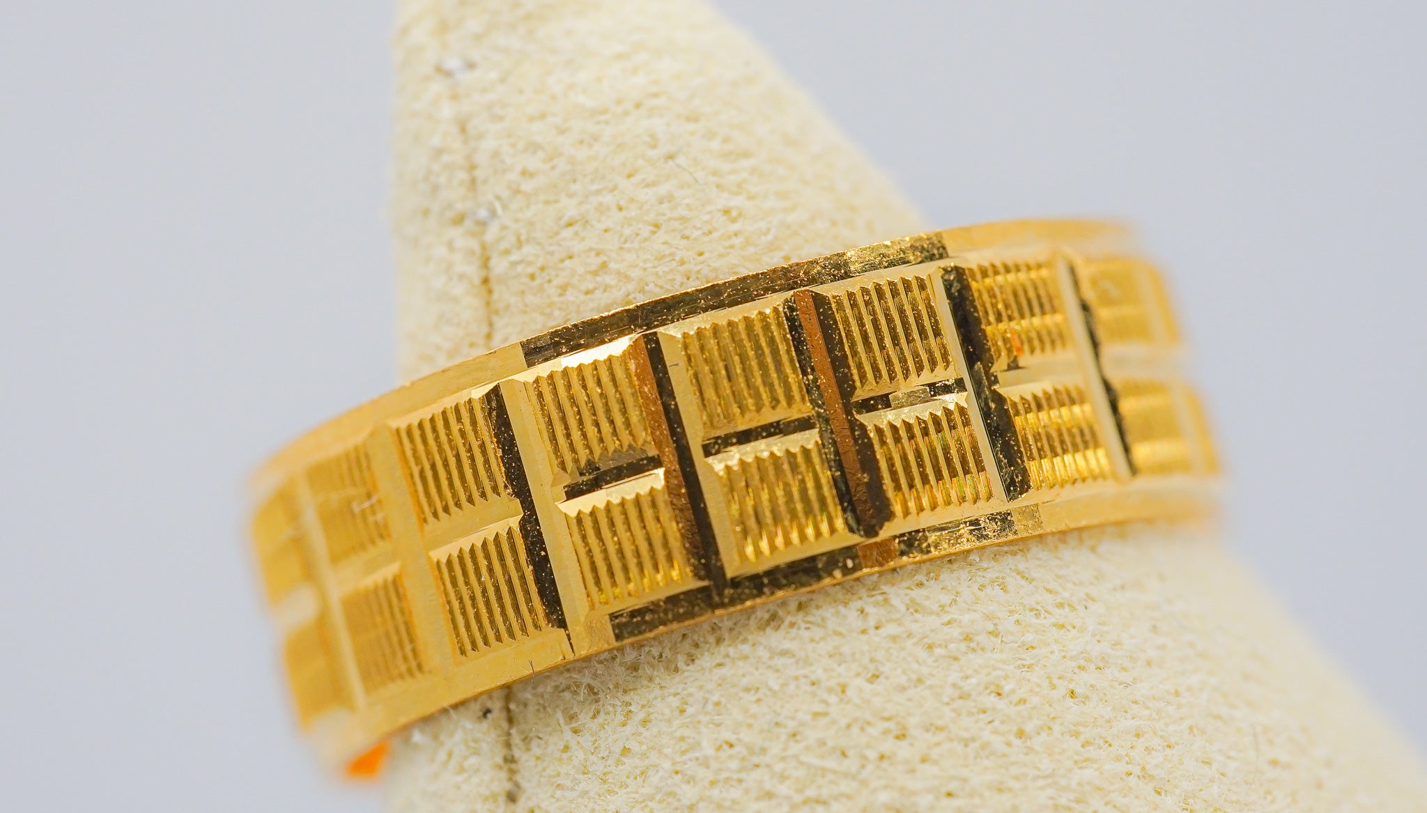 22K gold wide band ring with geometric rectangular pattern, size 7, shown on ring display.