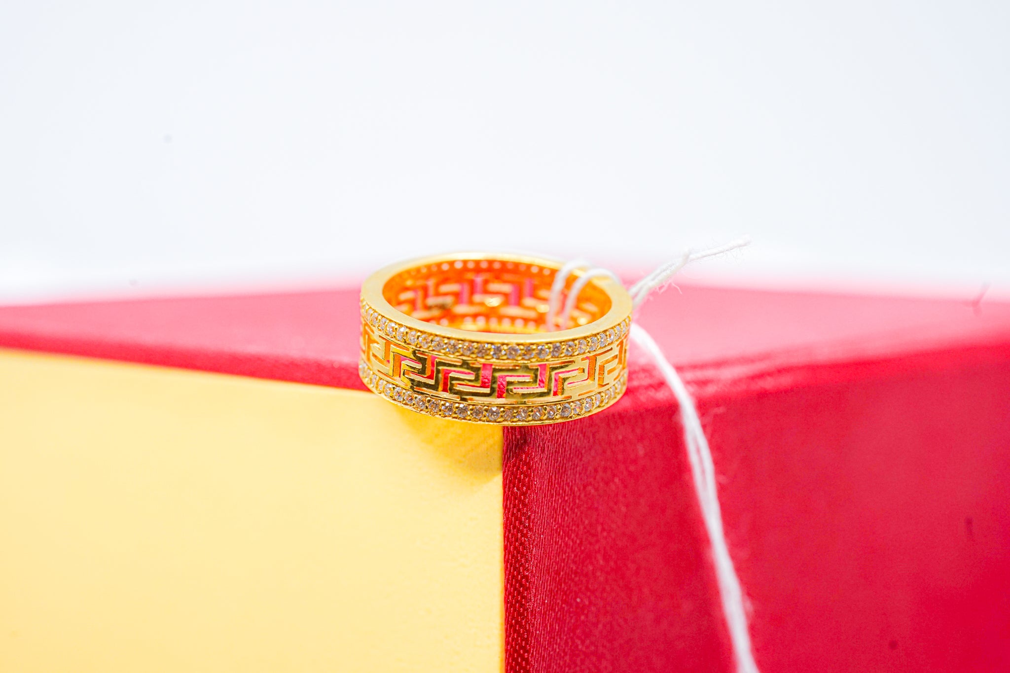 22K yellow gold Greek key band ring with clear stone edge accents.