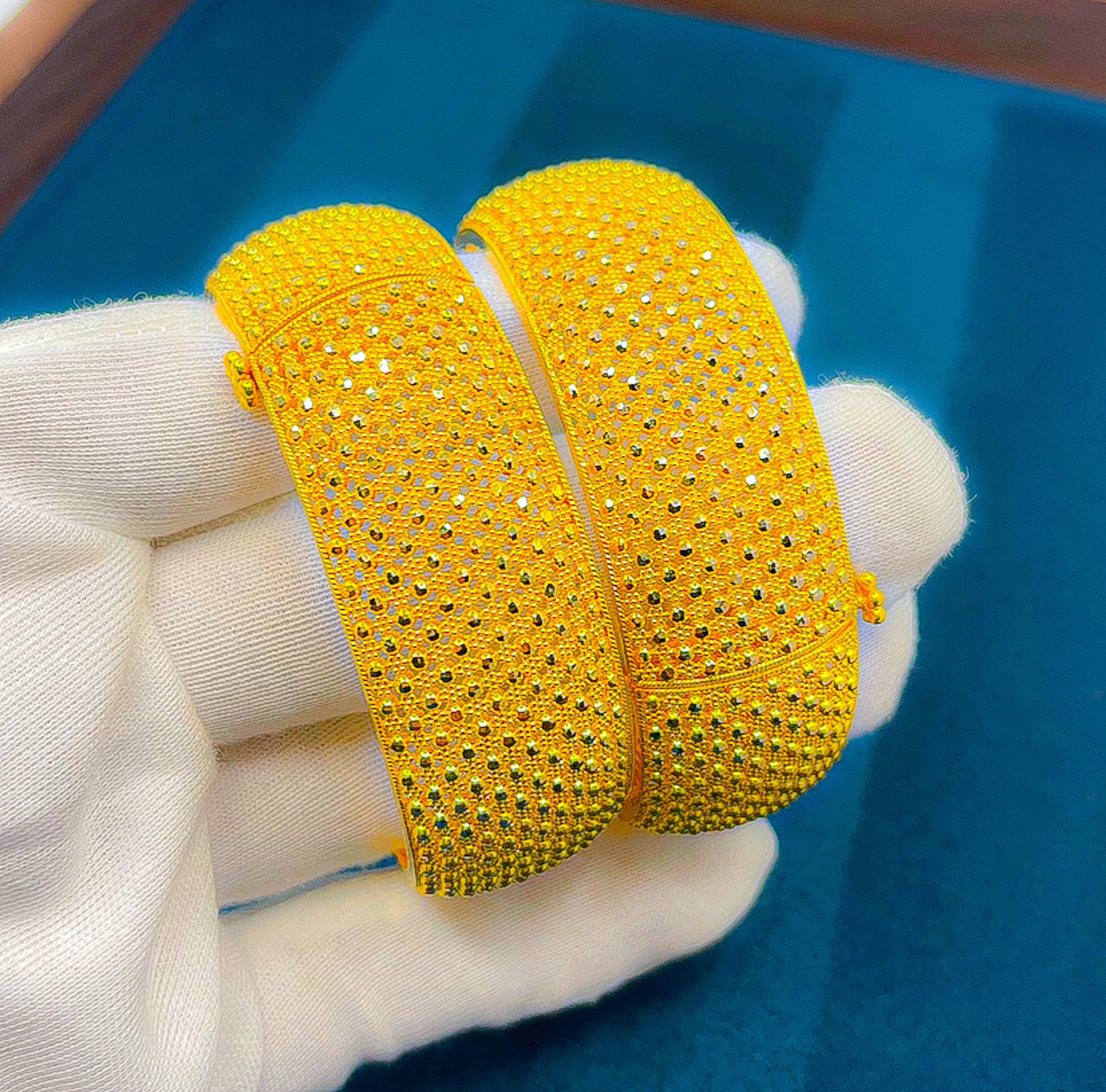 22K yellow gold wide textured bangles set shown on white glove