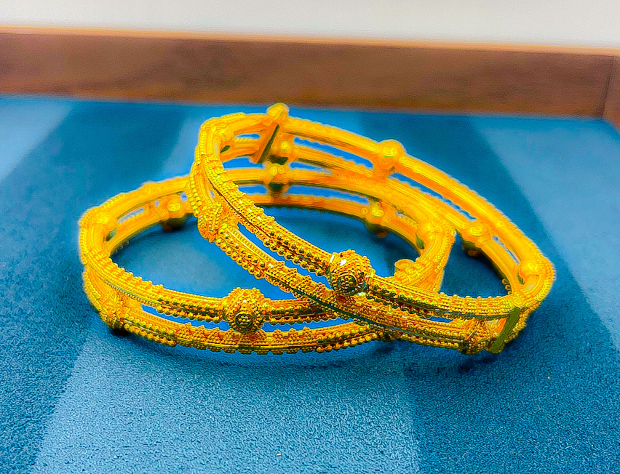 22K yellow gold bangle bracelet set (2 PCS) with textured design on blue background