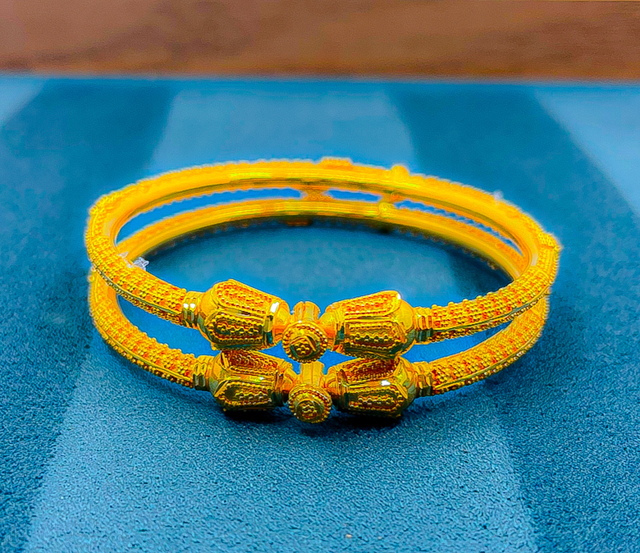 Two 22K yellow gold bangles featuring decorative center elements and textured finish