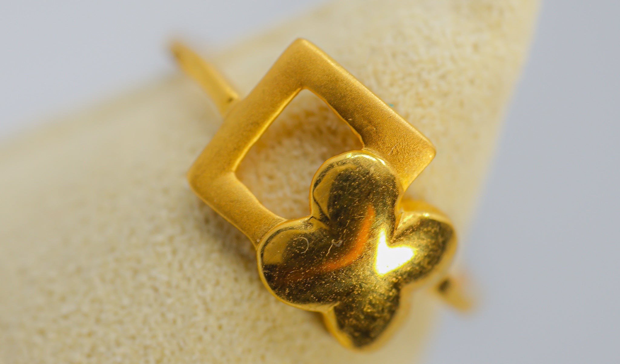 22K gold ring with geometric square frame and clover motif, close-up front view.