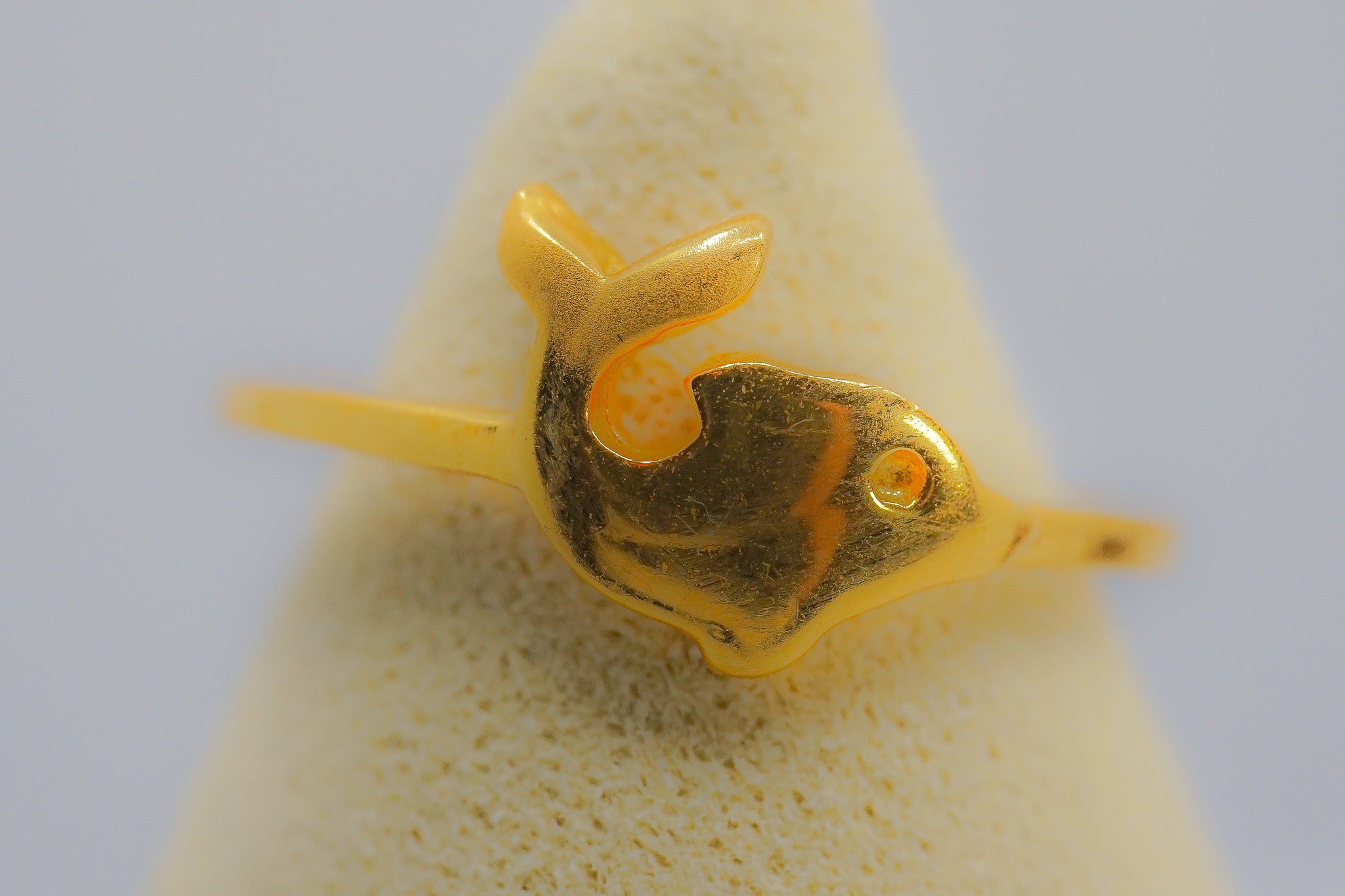 Angled view of a dainty 22k gold fish motif ring showing the thin band and polished finish.