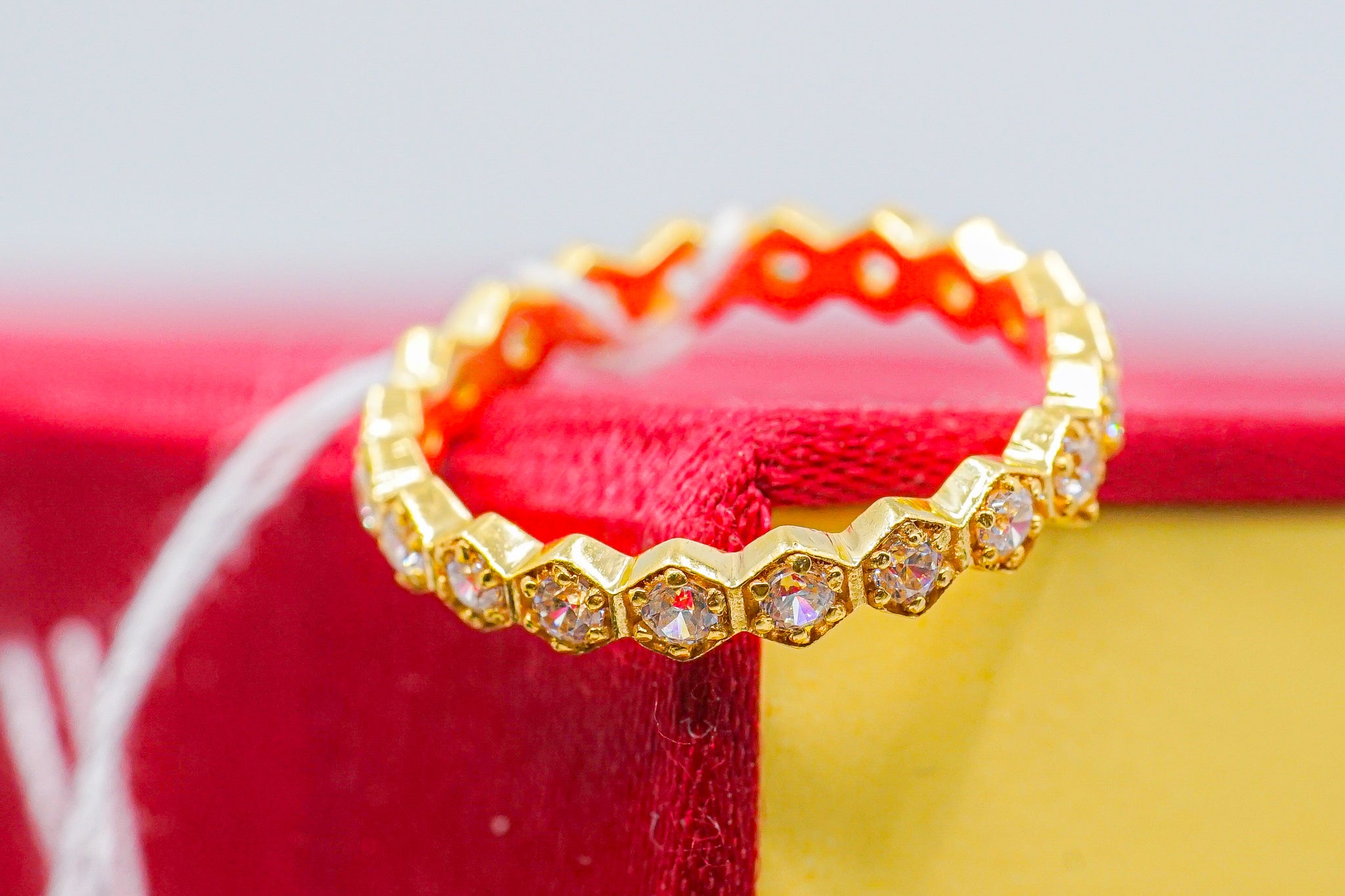 22k gold hexagon eternity band with clear stones, shown on red and yellow box