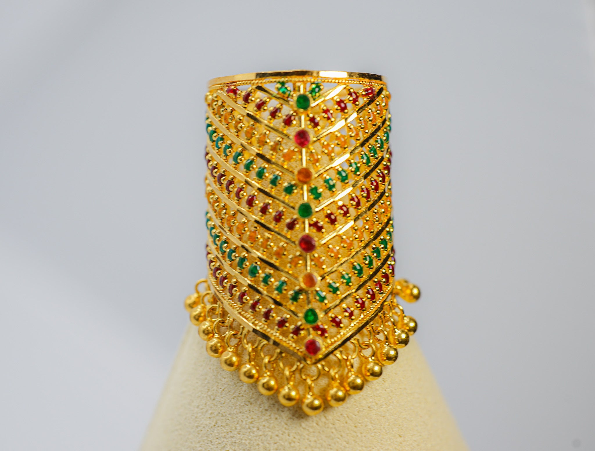 Front view of a 22K gold tall statement ring with red and green stones and dangling bead fringe, size 9.5.