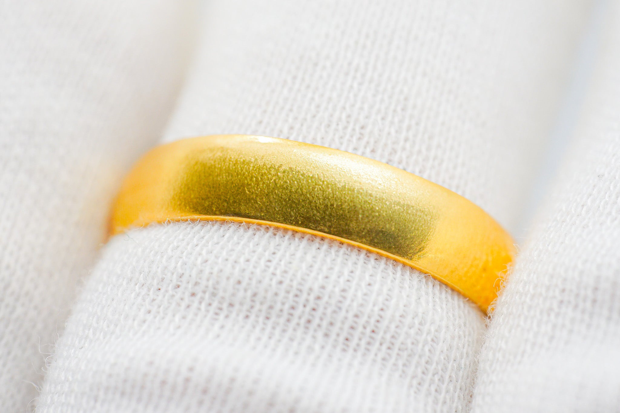 Smooth plain 22k gold band ring displayed on a cone stand against a light background.