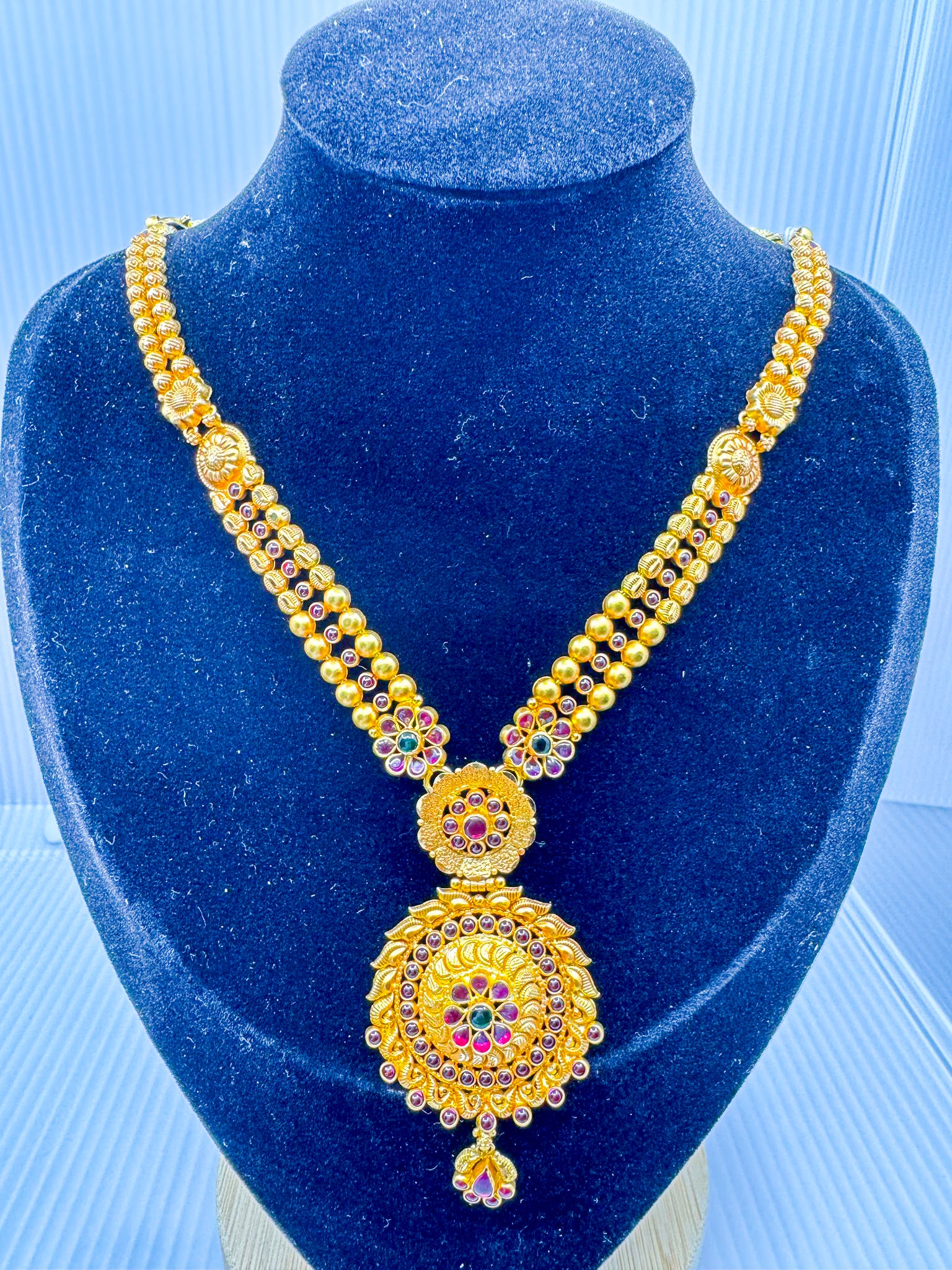 22k gold temple jewelry necklace with round statement pendant on display bust