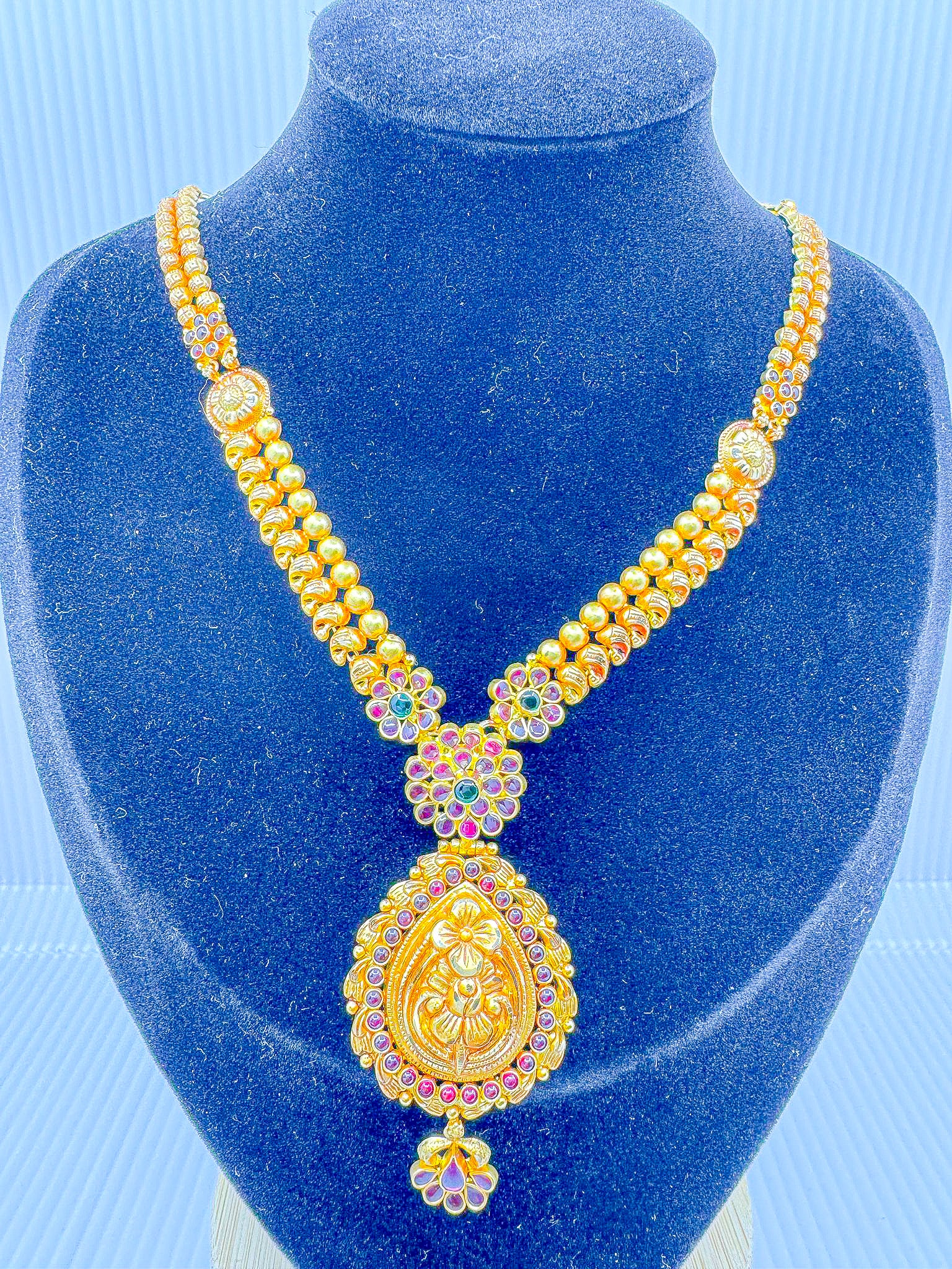 22k gold temple jewelry necklace with beaded chain and pendant, front view on blue display bust