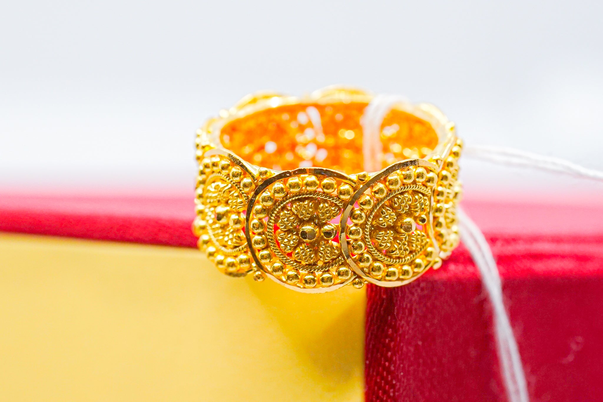 22k gold wide band ring with raised round medallion-style detailing,