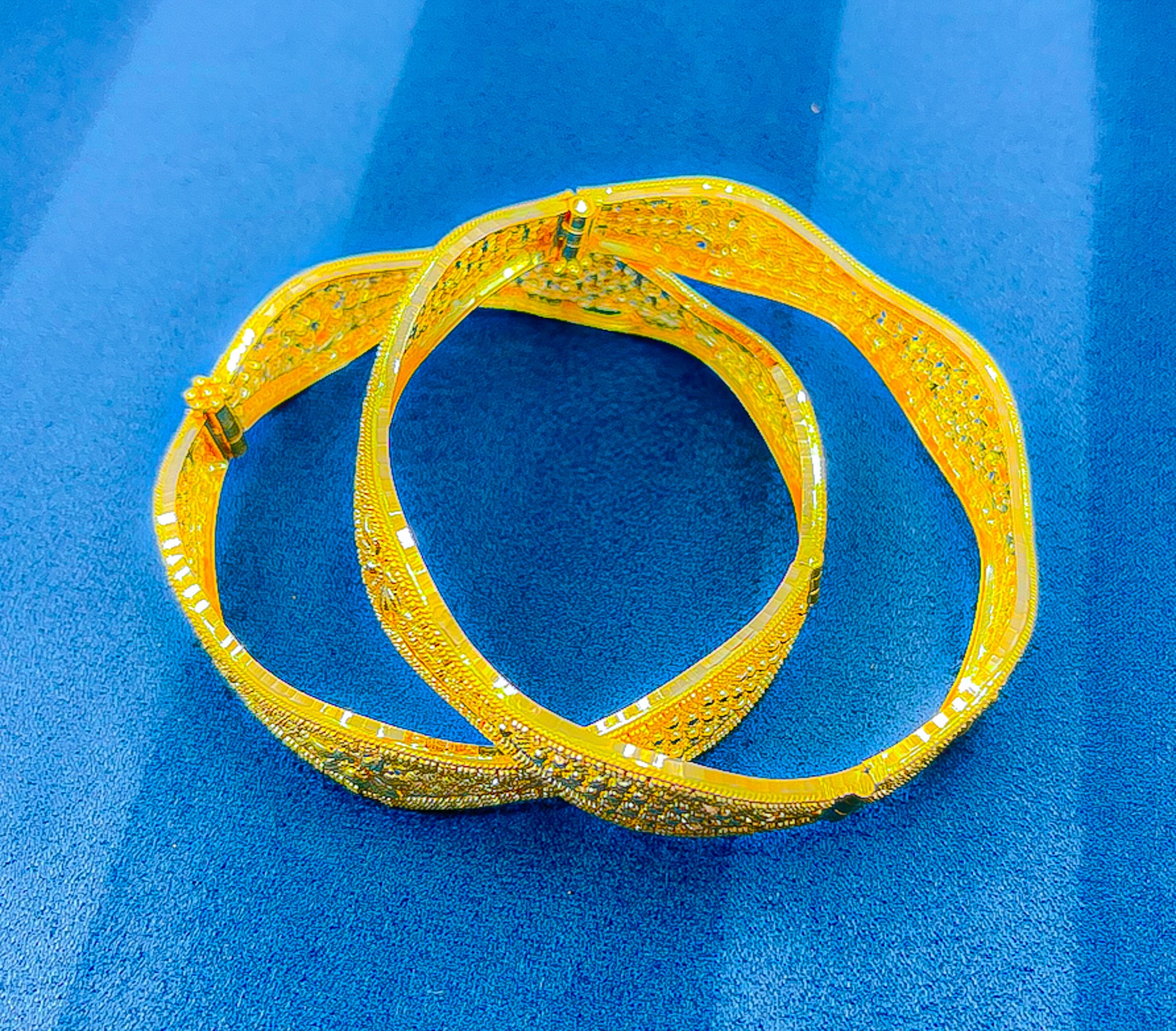 22k yellow gold bangle with intricate traditional patterned detailing photographed