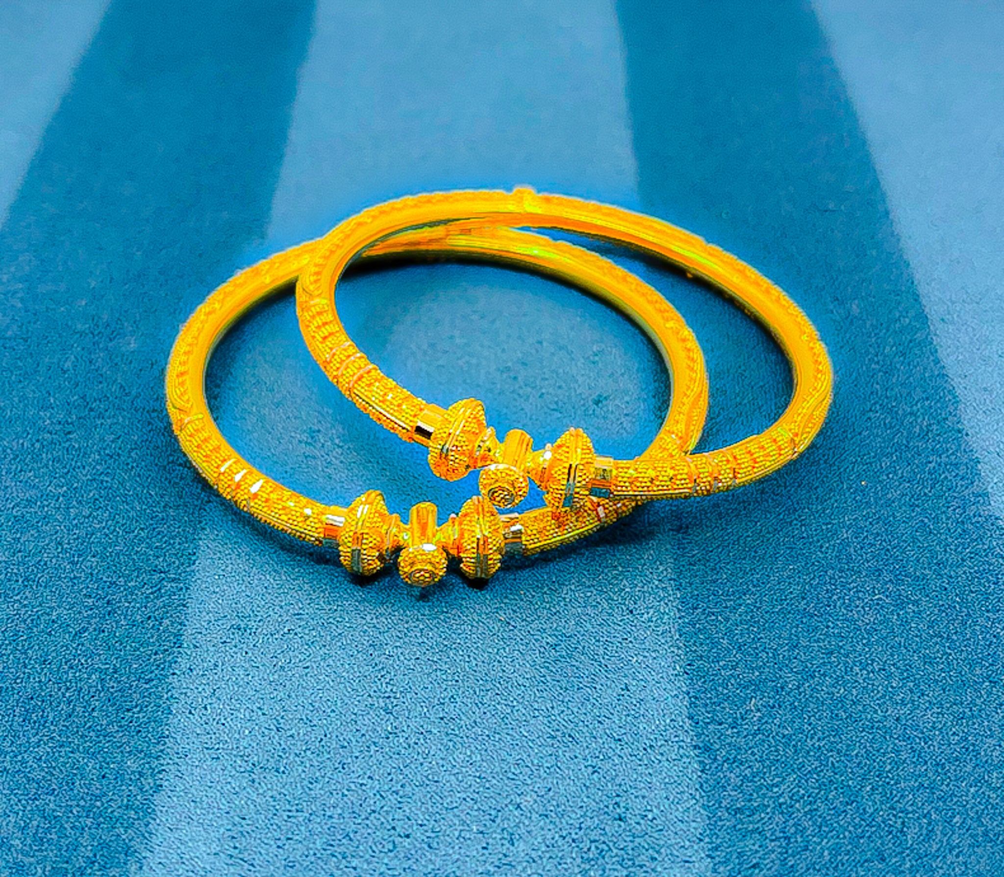 Front view of 22K yellow gold bangle set showing decorative end detailing and textured design