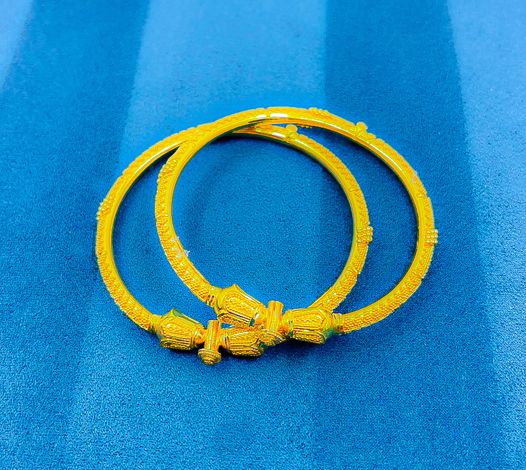 22K yellow gold bangles featuring decorative center elements and textured finish