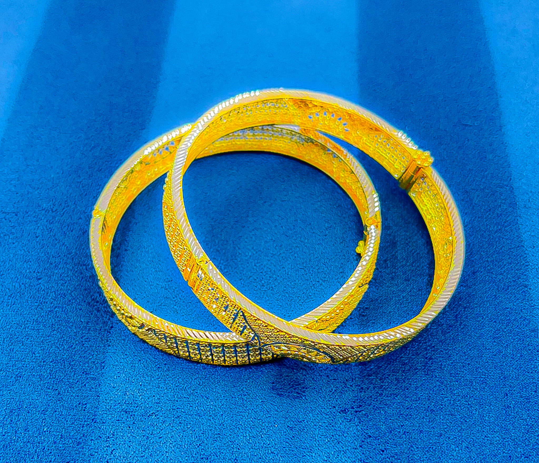 22k yellow gold wide bangle with textured patterned design on blue background