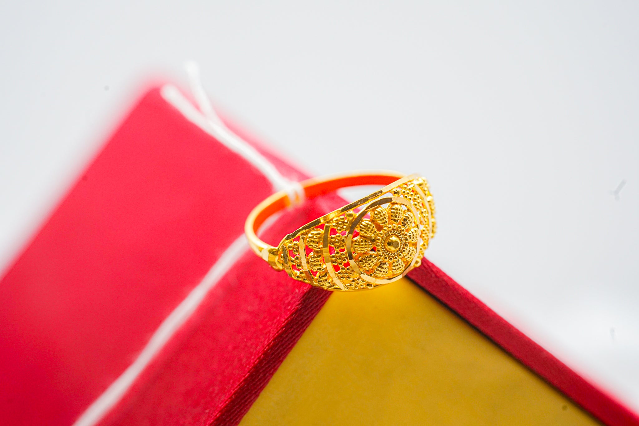 22k gold floral dome ring with beaded details on a wooden box next to a red jewelry box