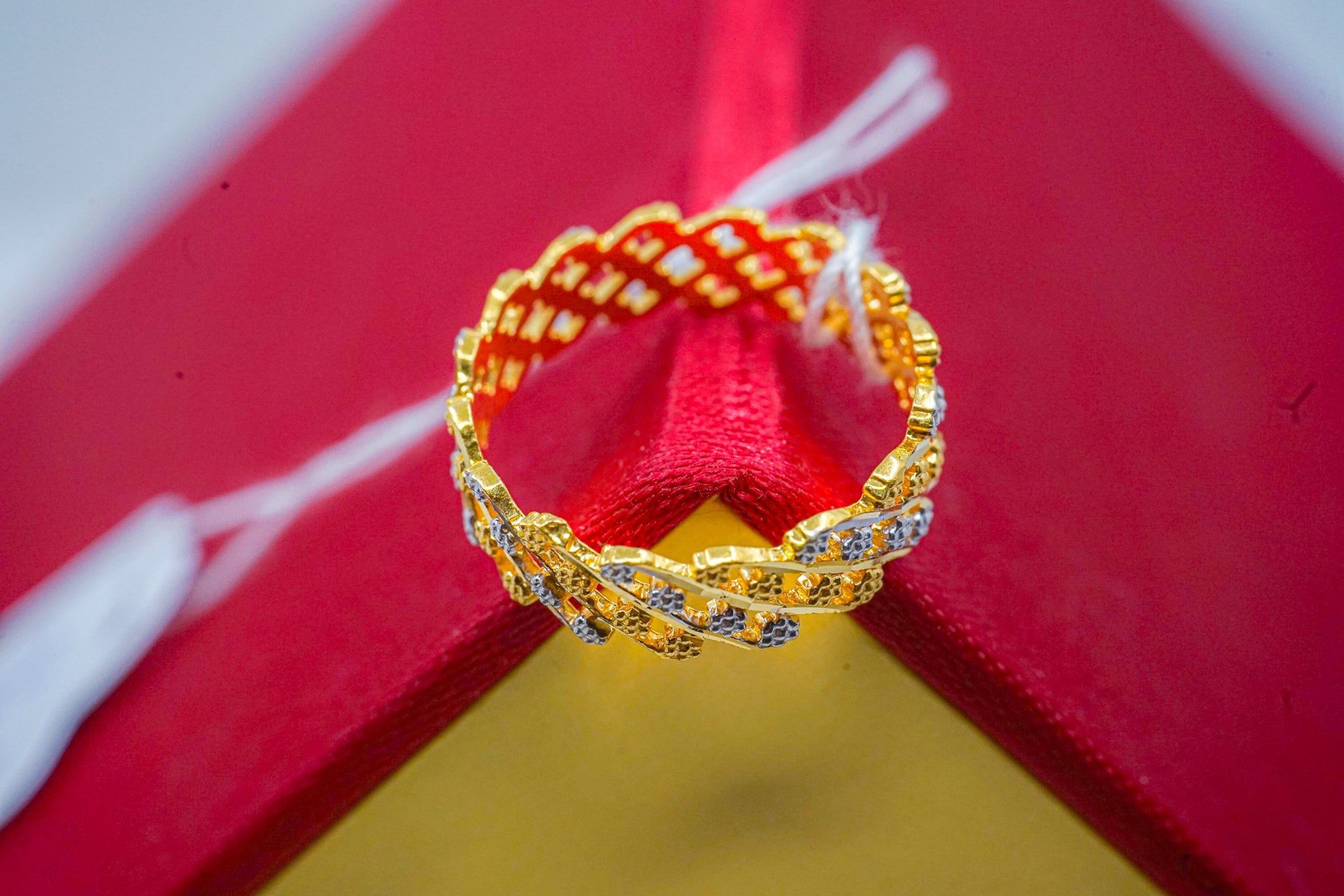 22k gold band ring with geometric patterned design on red and yellow background.