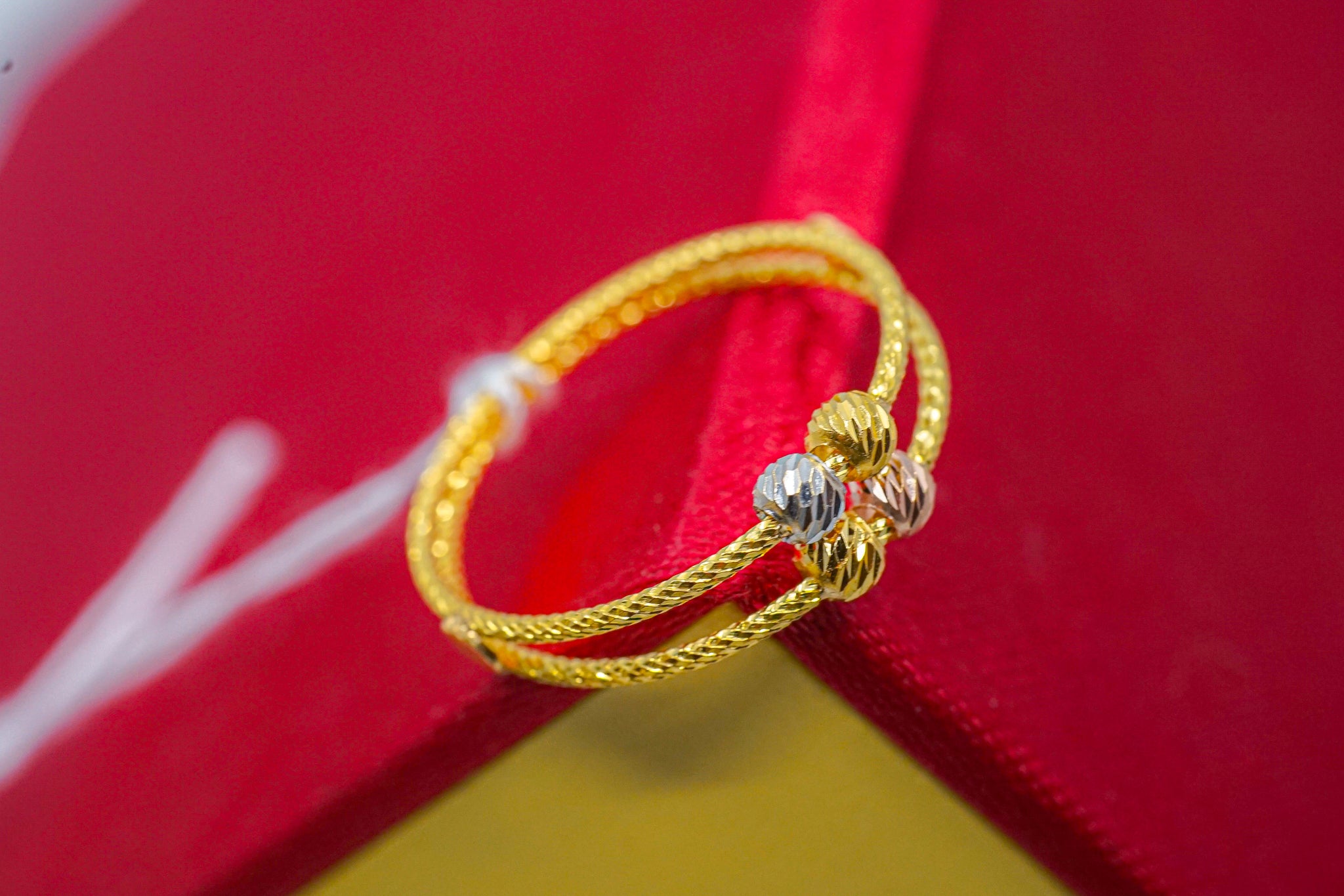 22k gold double twisted rope band ring with three bead accents on a red and yellow box.