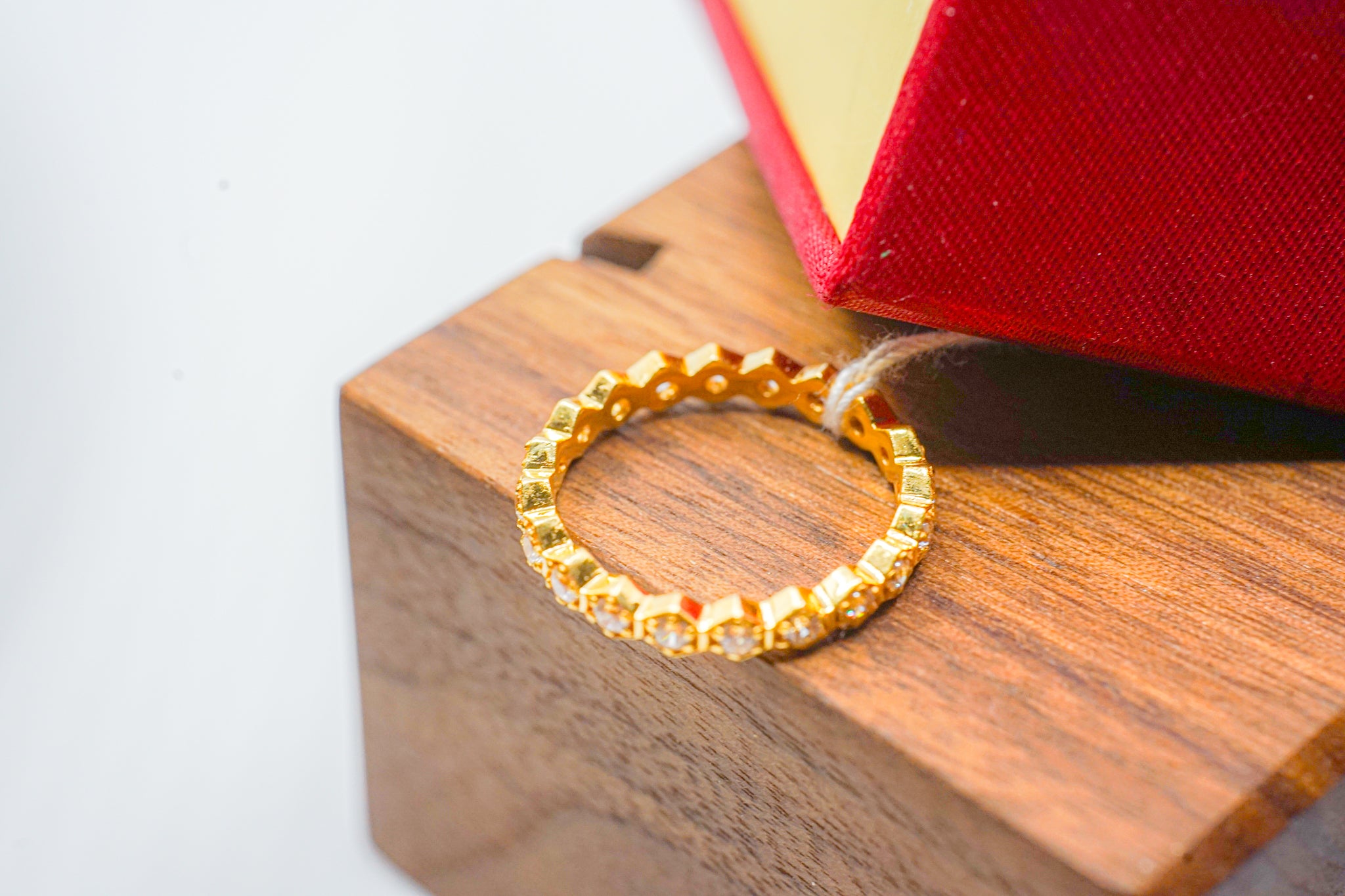 22k gold eternity band ring with small round clear stones on a wooden surface