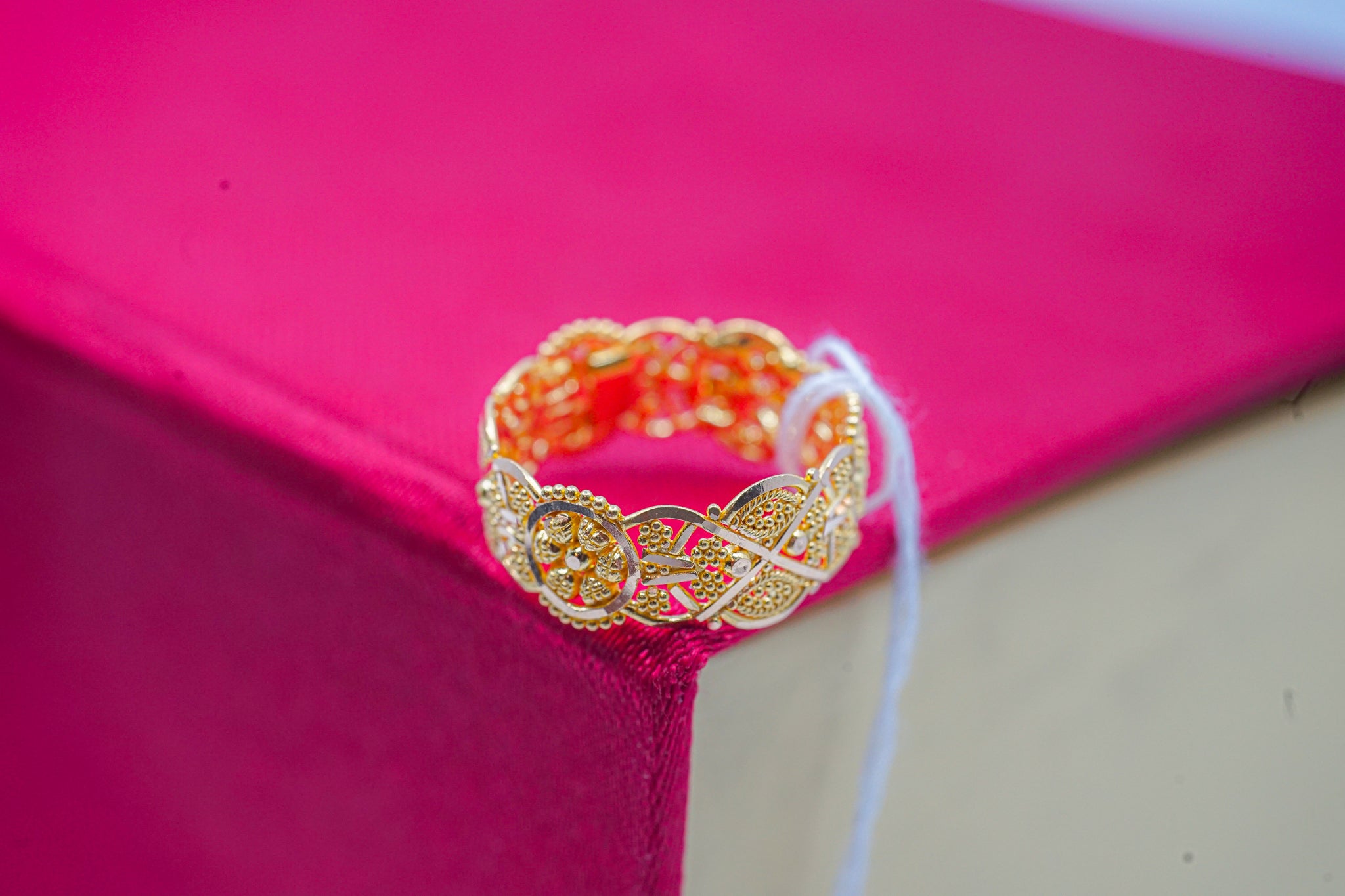 22k gold floral filigree band ring, front view, on pink box background