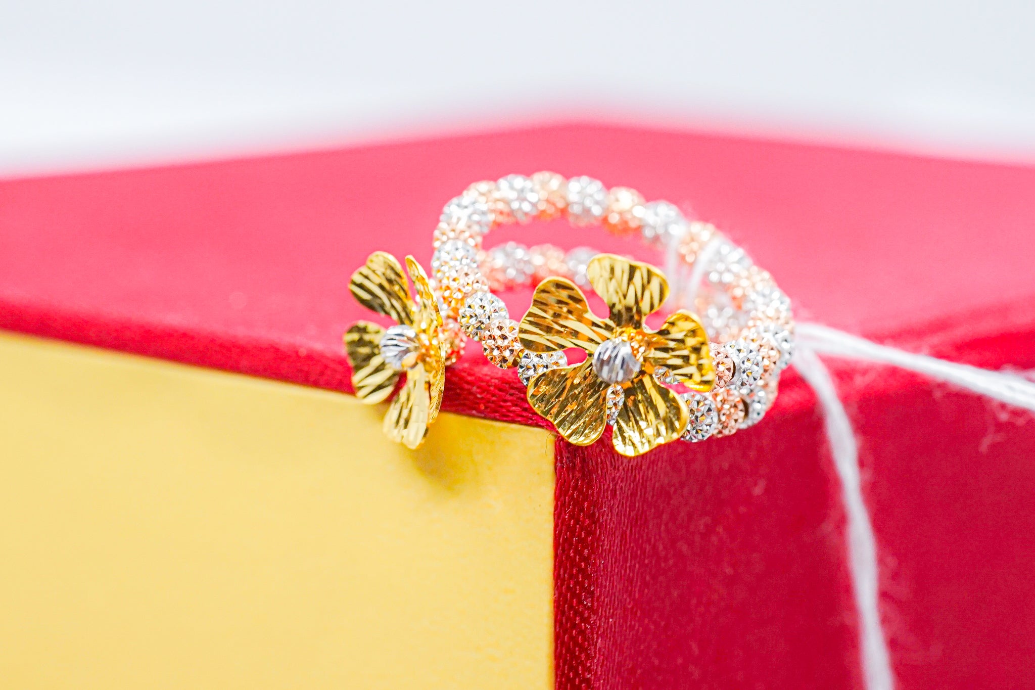 22k gold floral ring showing the split band and flower details, photographed on a display stand.