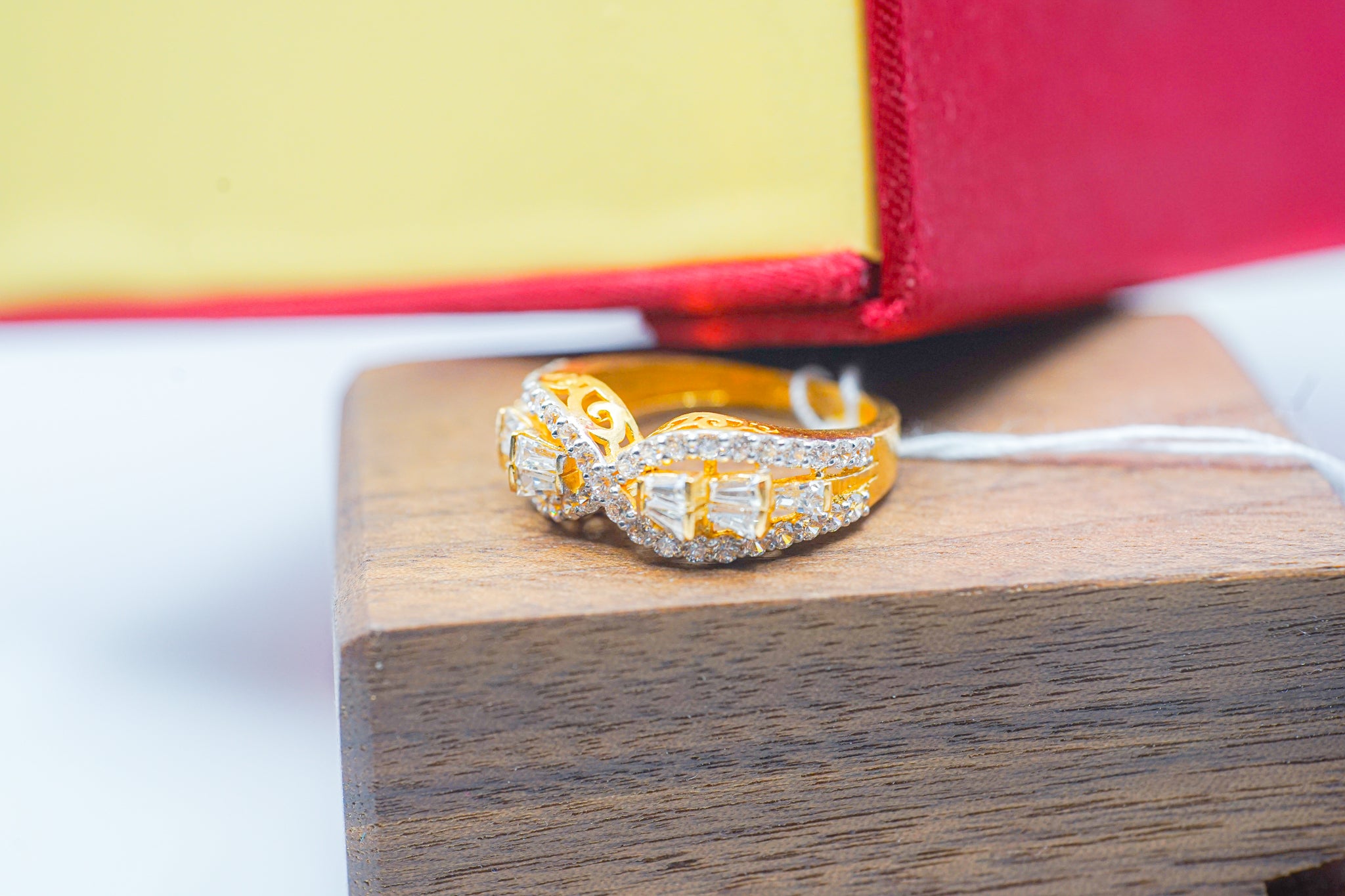 22k gold infinity crossover ring with clear stones and baguette-style accents, shown on a wooden block