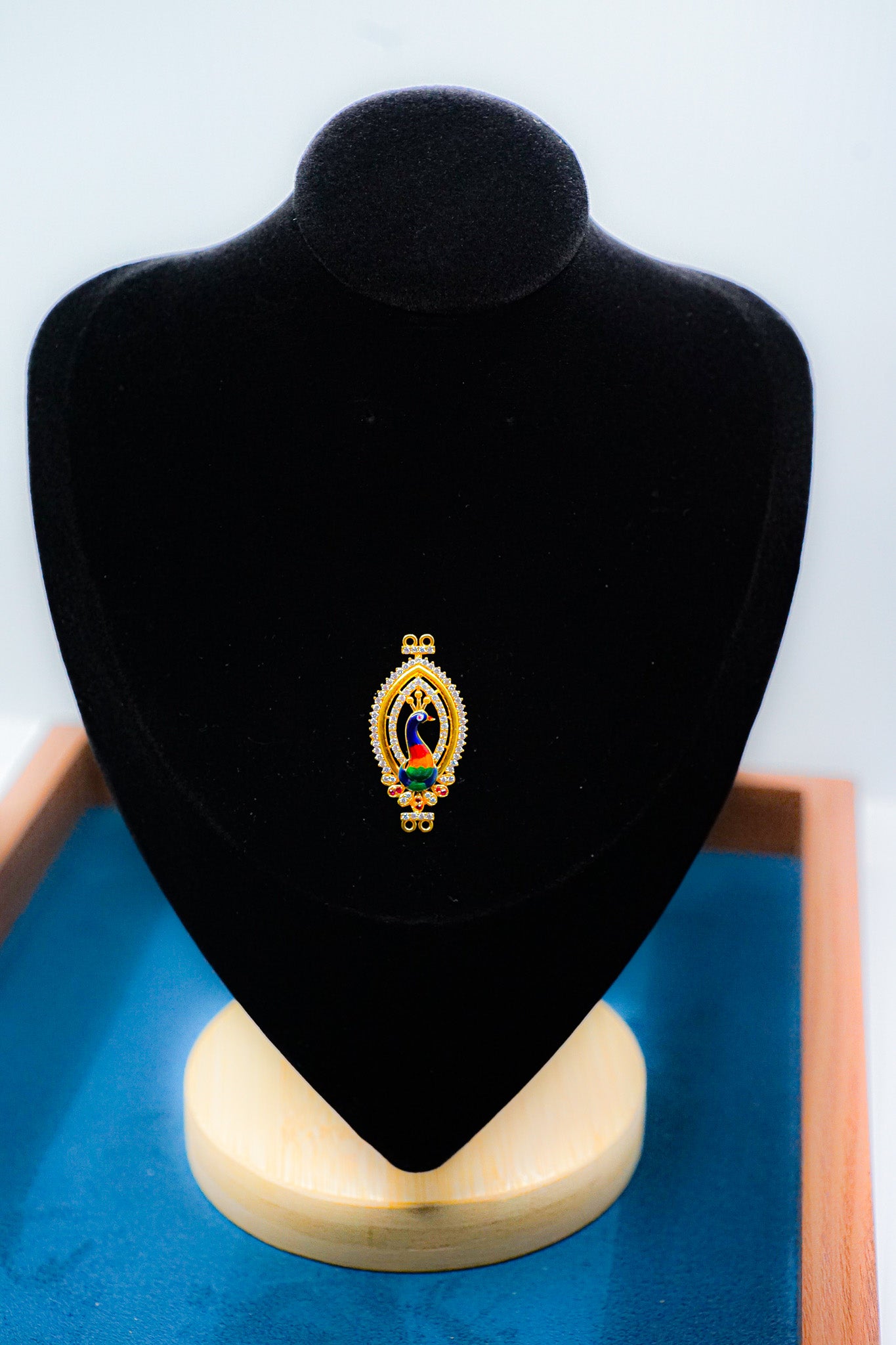 22k gold oval pendant with multicolor detail displayed on a black jewelry bust.