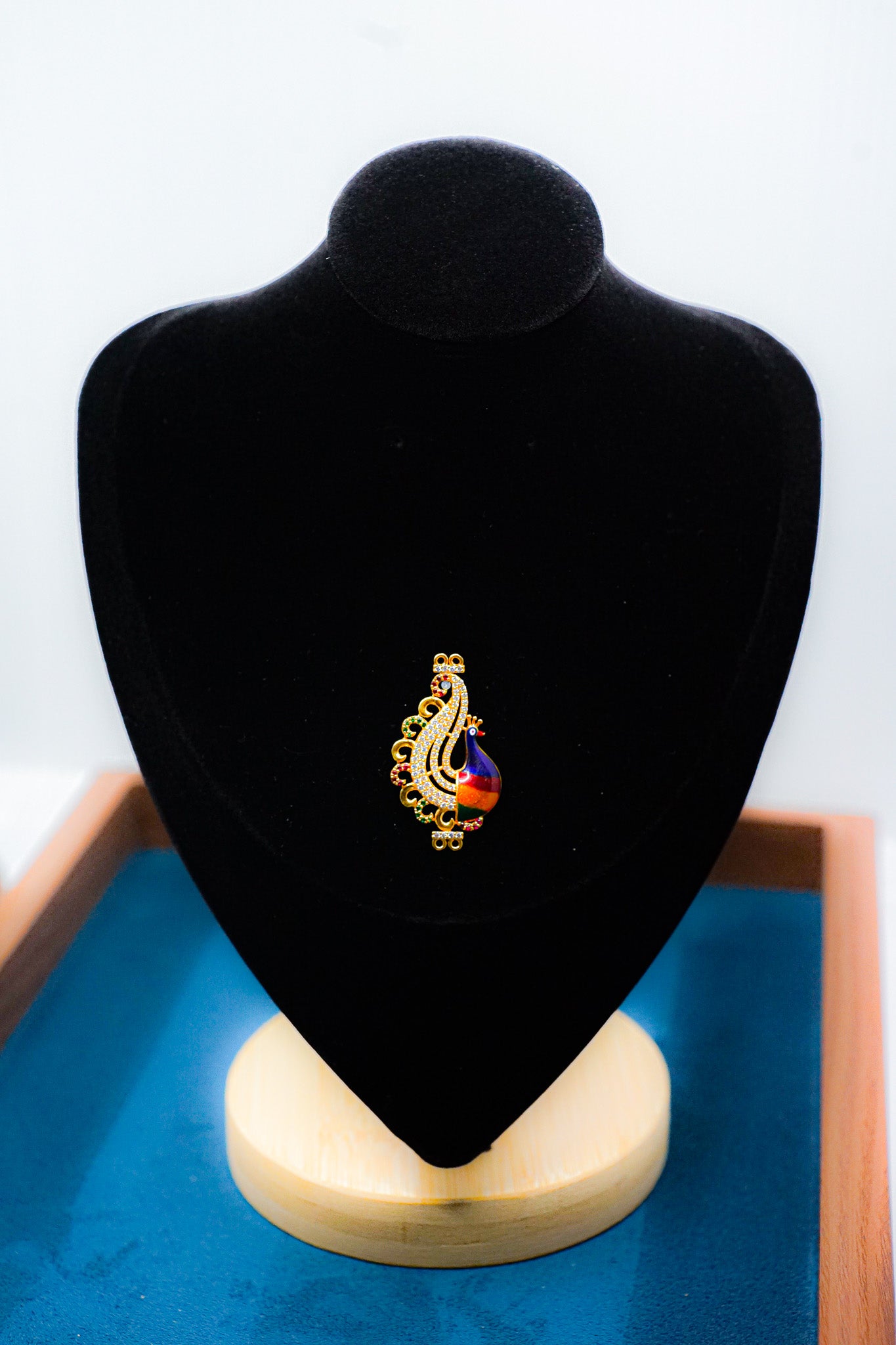 22k gold paisley pendant with multicolor teardrop accent on a black jewelry display bust.