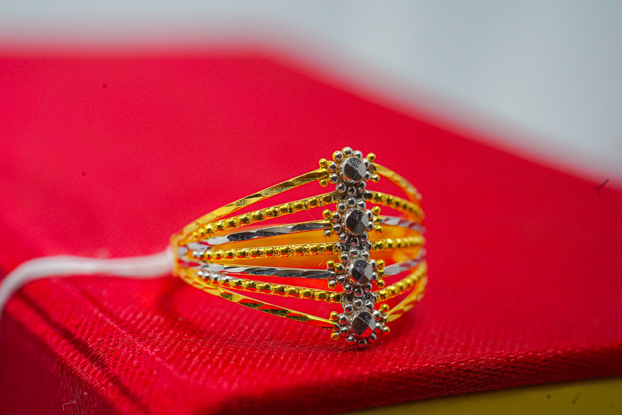 22k gold split shank ring with geometric multi-band design and dark accent top, shown on red box