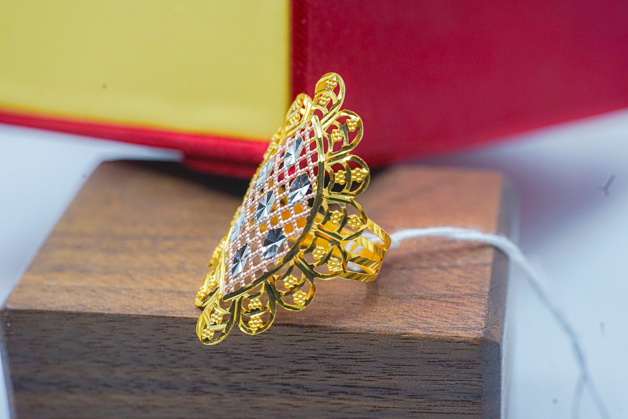 22k gold statement ring with a geometric square top and mixed-tone accents on a wooden surface