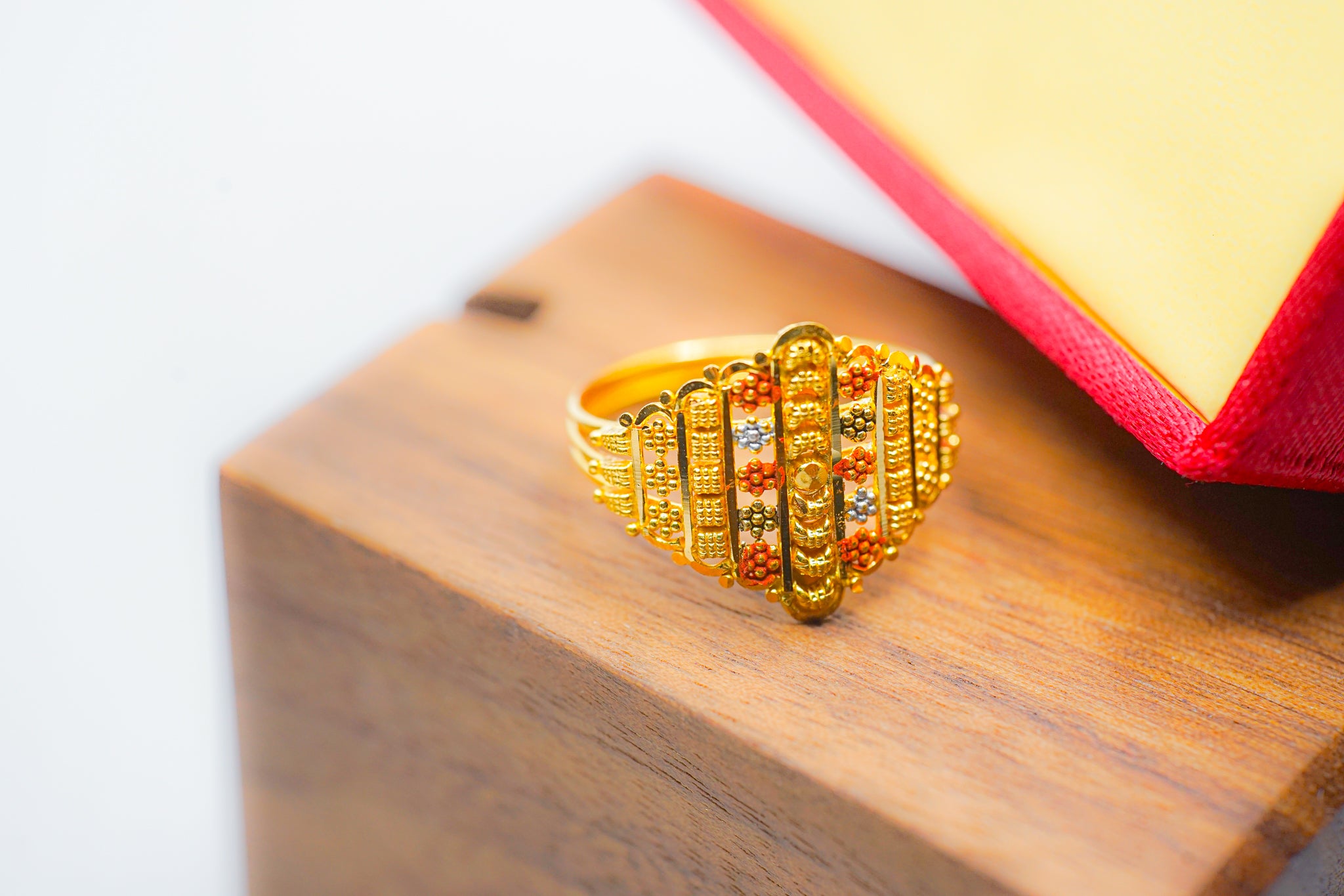 22k gold wide band ring 3.25g with textured beaded design and red and silver-tone accents on a wooden block