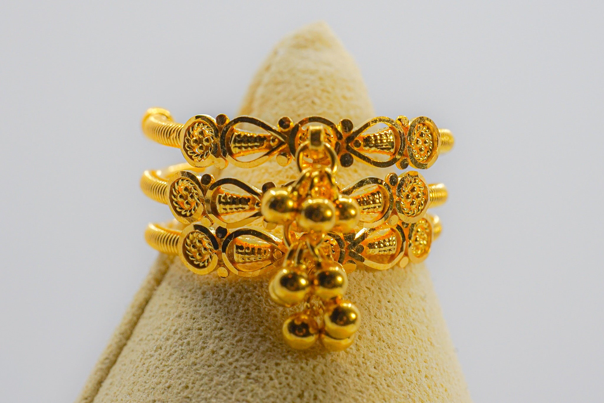 22k yellow gold beaded multi-row ring with dangling bead charms on a display cone