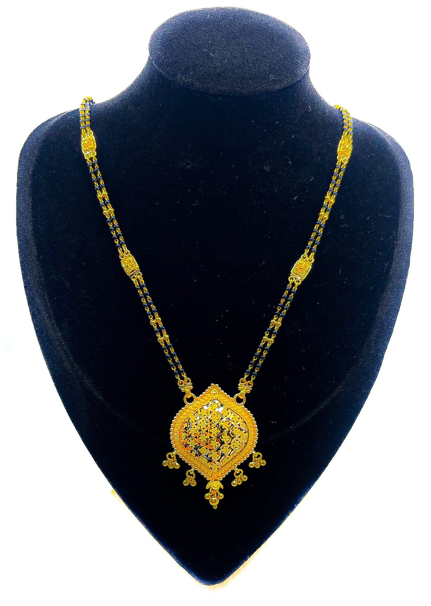 22k yellow gold necklace with black beaded chain and decorative pendant displayed on black velvet mannequin bust