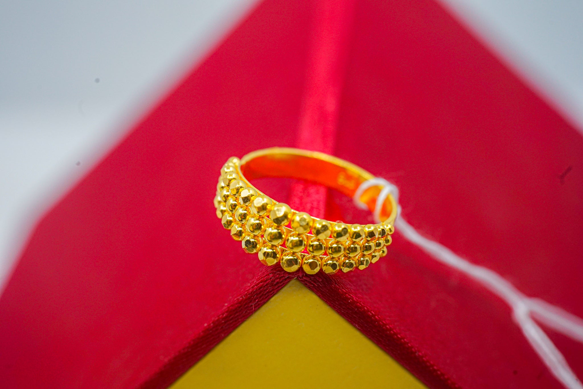 22K yellow gold beaded statement band ring (3.39g) shown on red and yellow background.