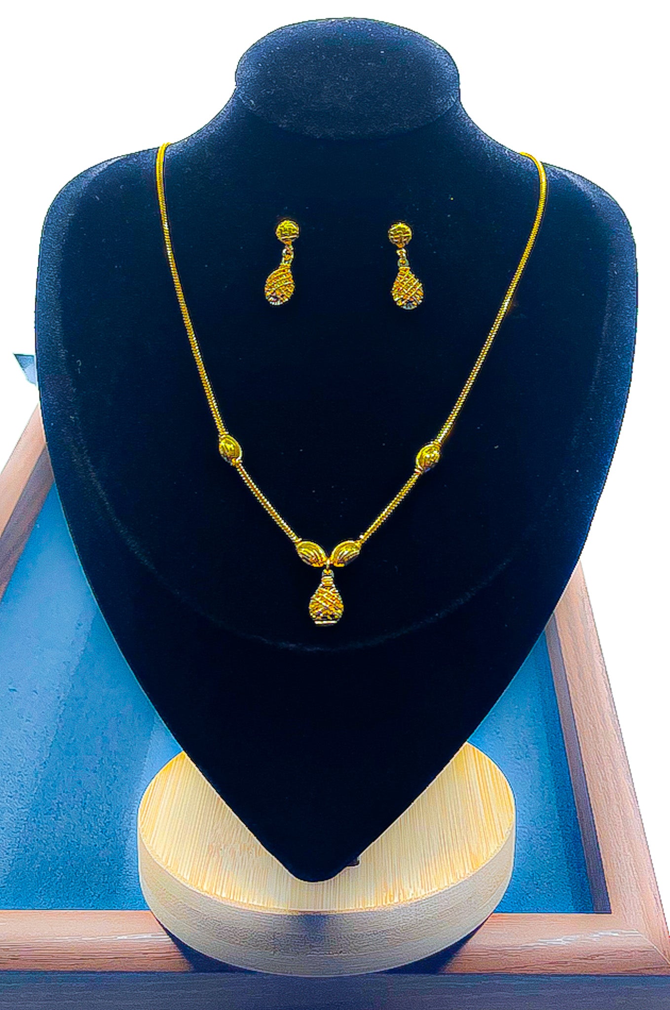 22k gold necklace and matching drop earrings set displayed on a black velvet bust with a blue tray base.