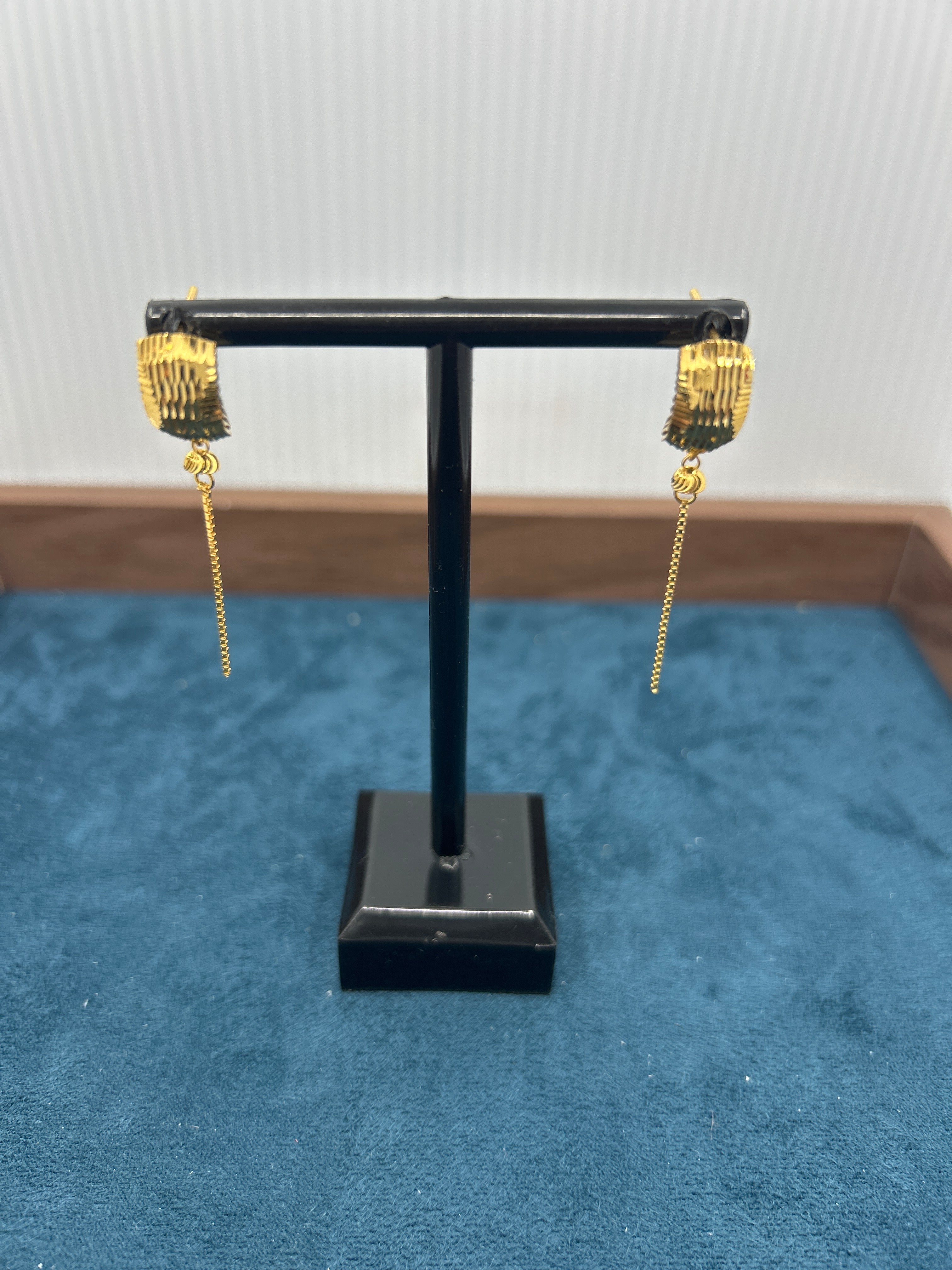 Gold long chain drop earrings pair on black stand