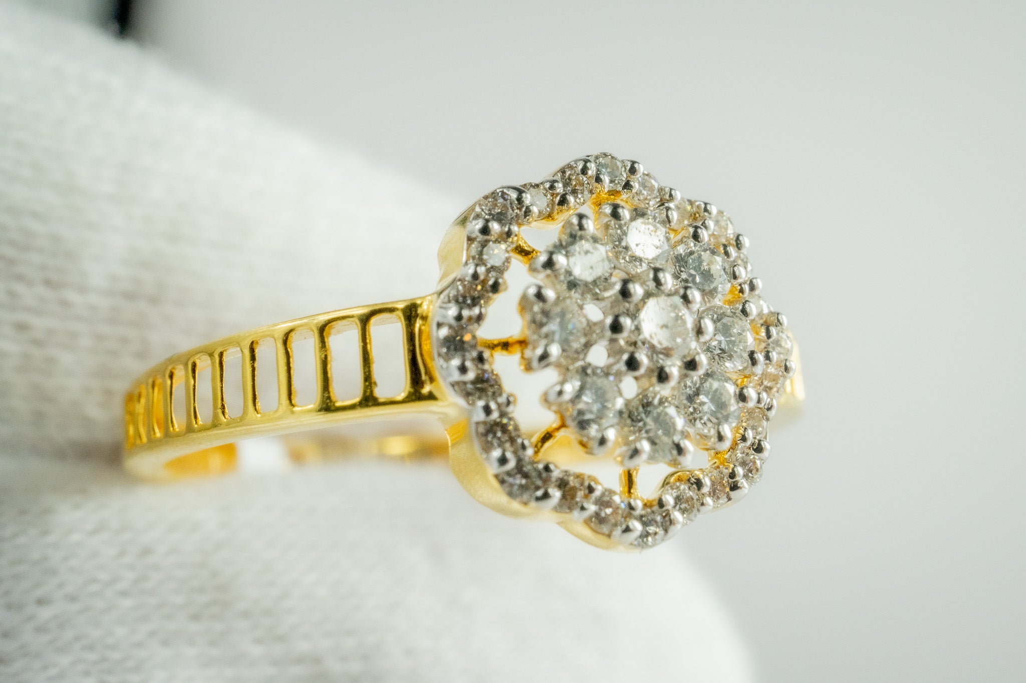 Close-up of 18k yellow gold diamond halo cluster ring showing cluster center and halo on white cushion