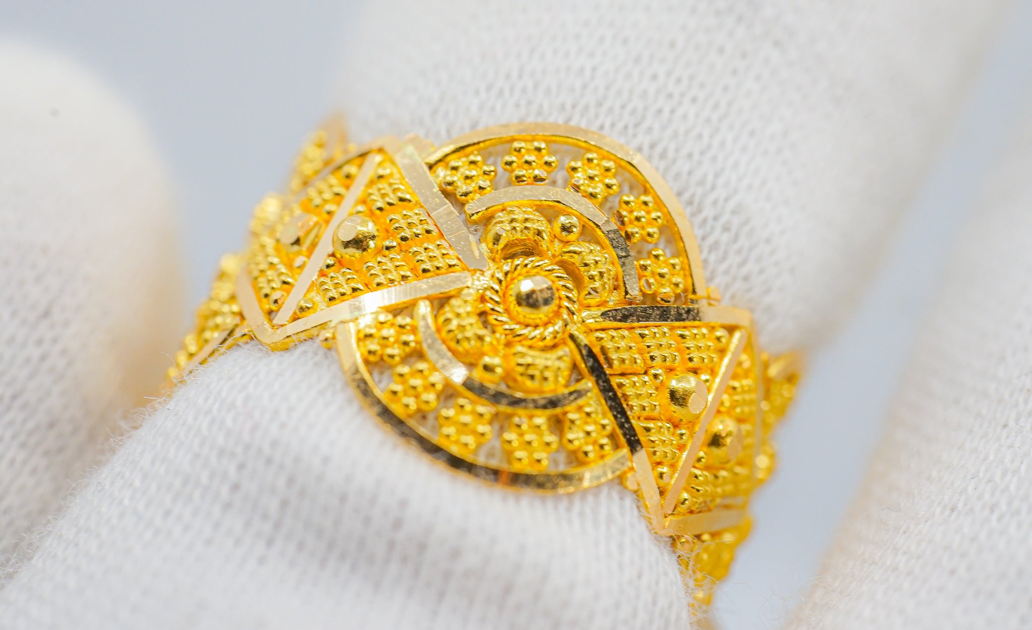 Close-up of 22K gold ring showing textured beaded pattern with circular and triangular design details.