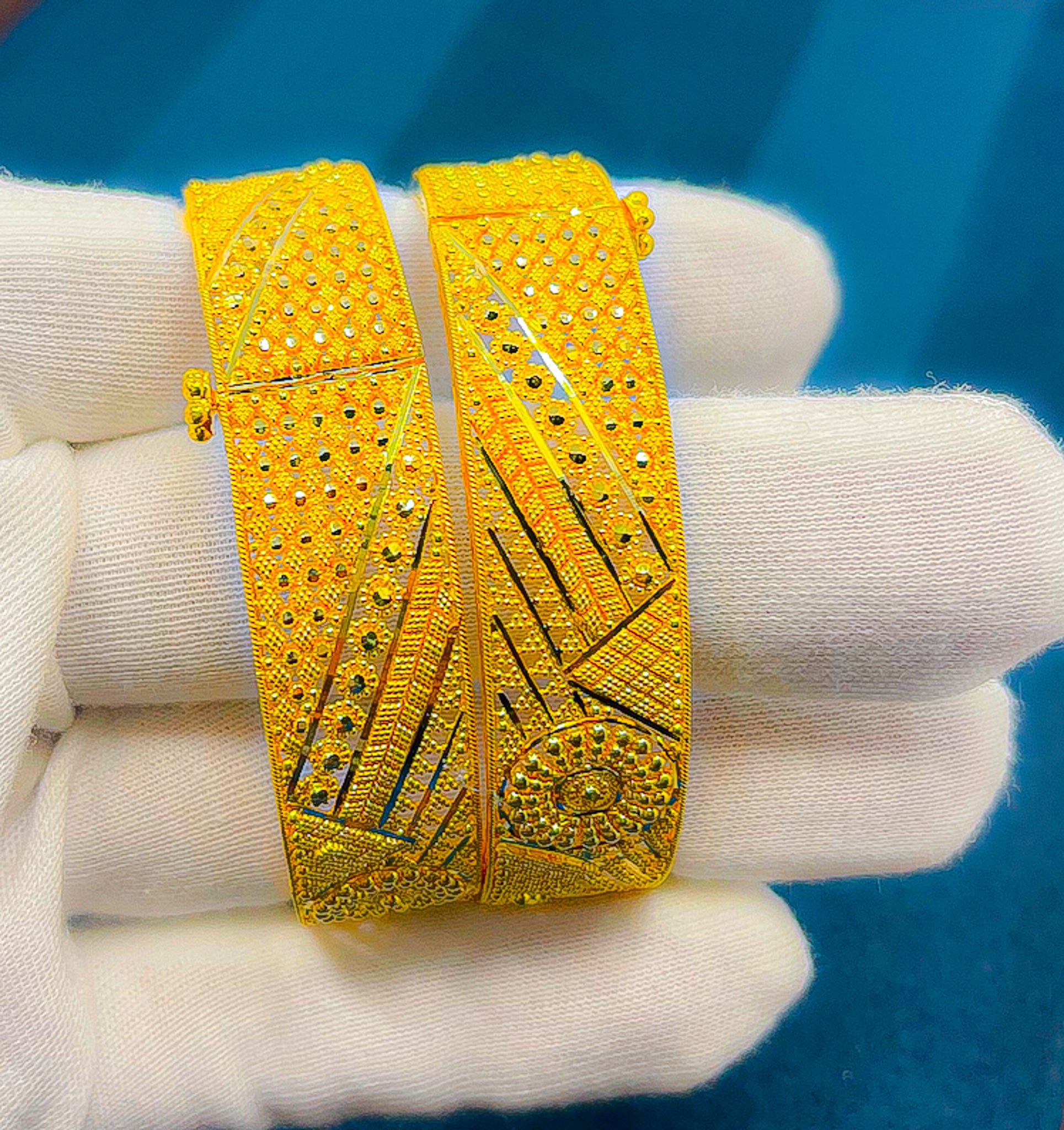 Close-up of 22K yellow gold wide bangle showing textured dotted design and clasp closure