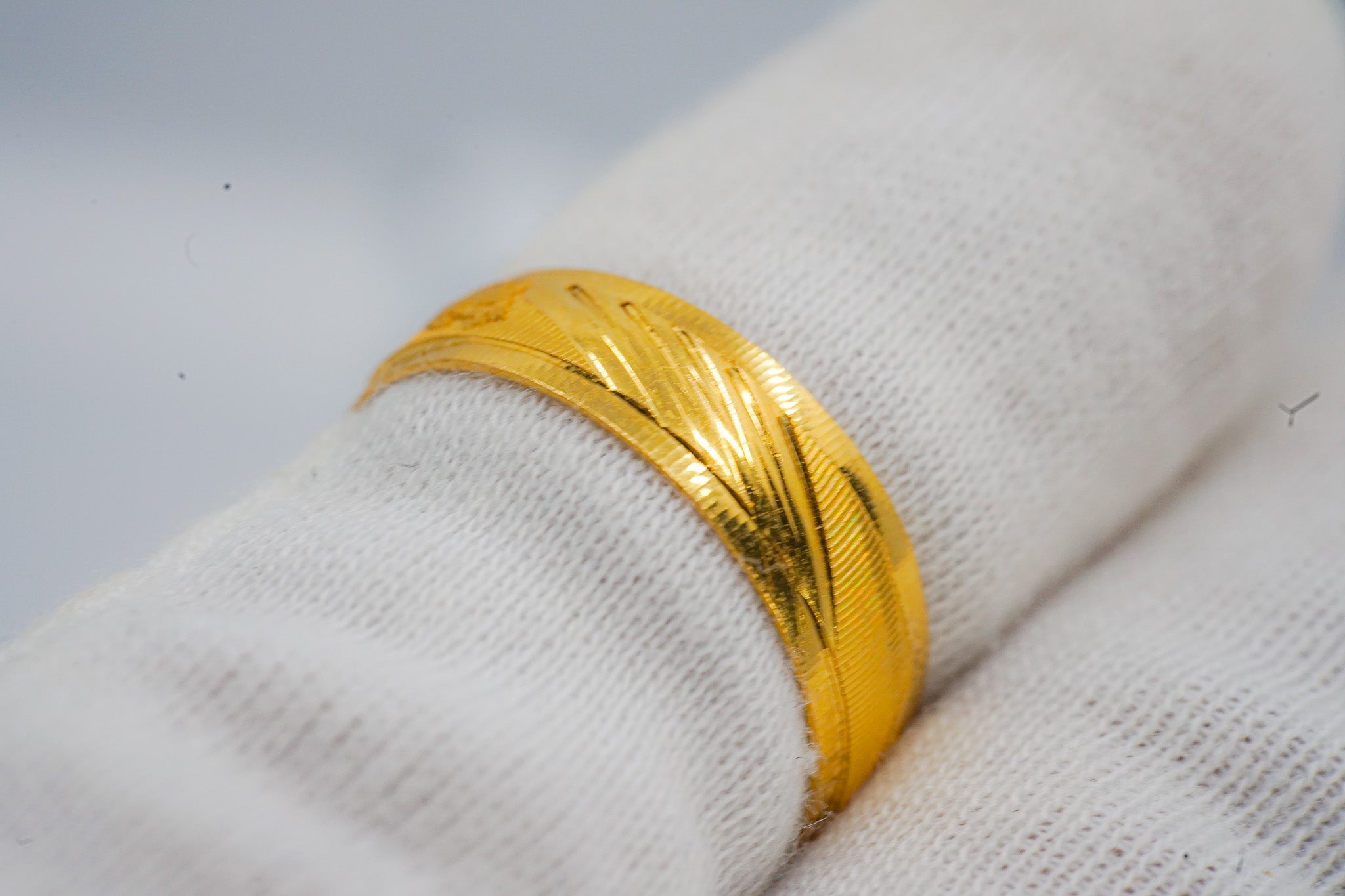Close-up of a 22k gold band ring showing the diagonal engraved textured pattern, size 8.