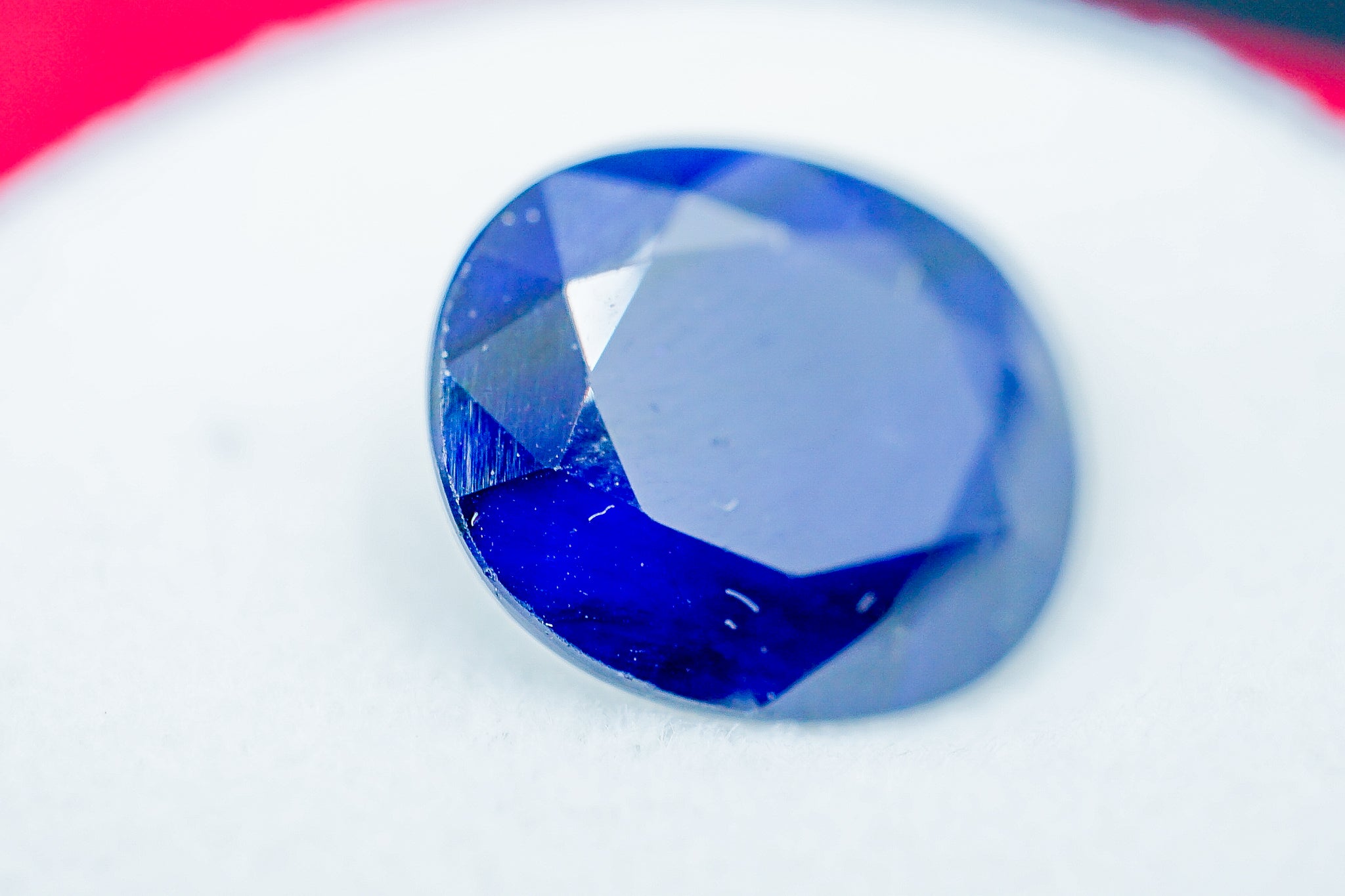Close-up of oval faceted blue sapphire loose gemstone on white background, 2.53 g