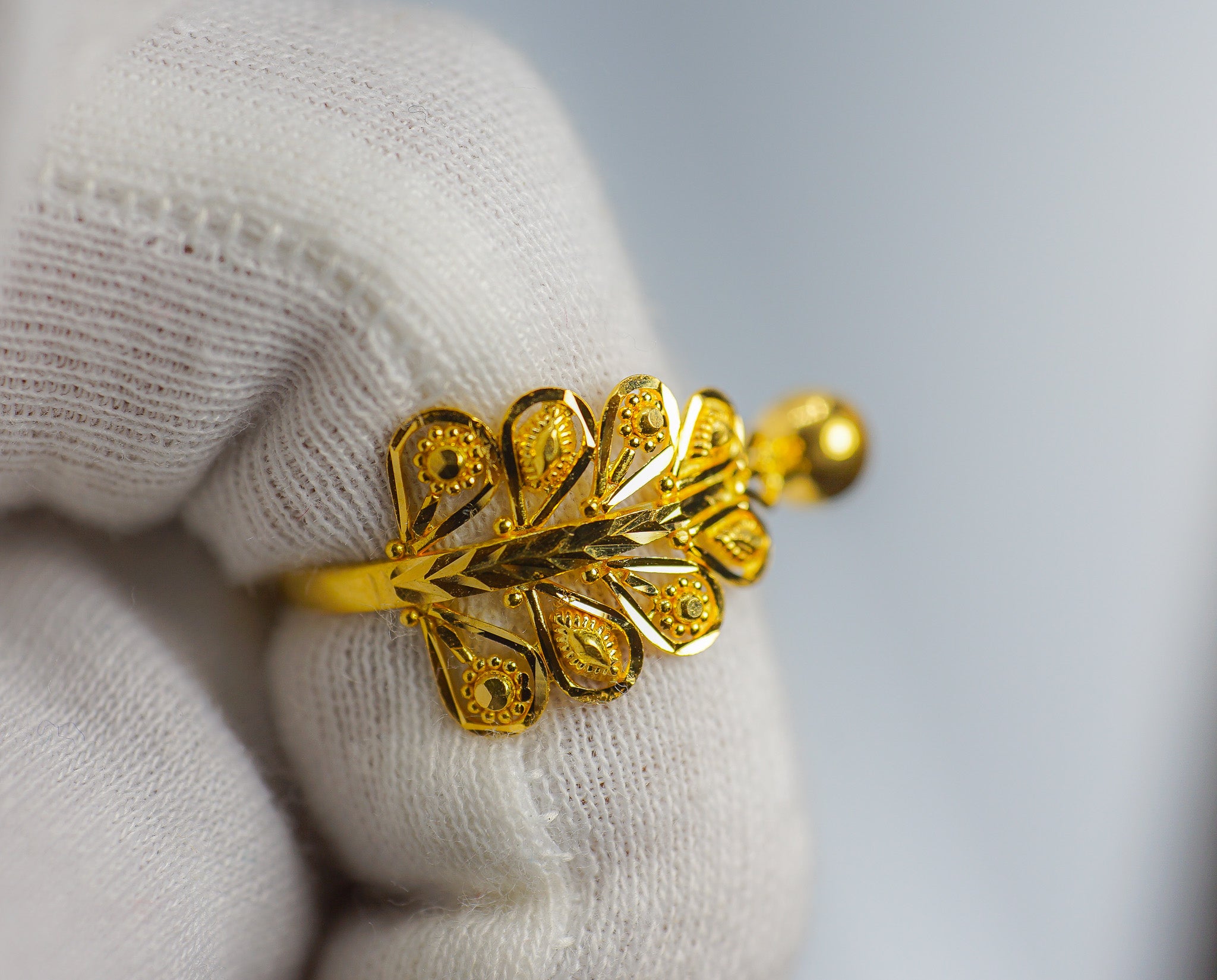 Close-up of the 22K gold leaf motif ring held with a white glove, size 9.5 (2.72g)