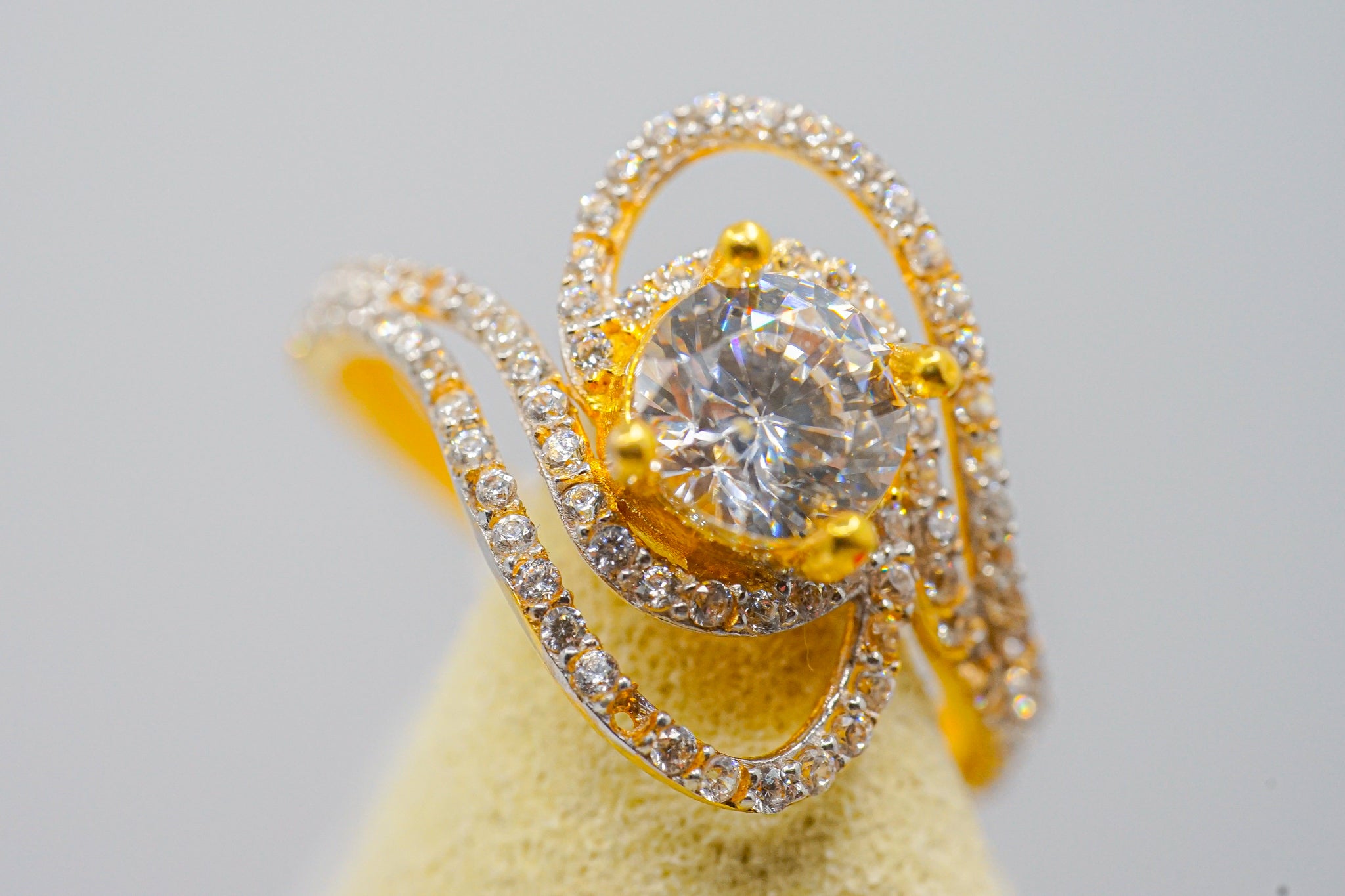 Close up of 22k gold zirconia solitaire ring with pavé swirl design