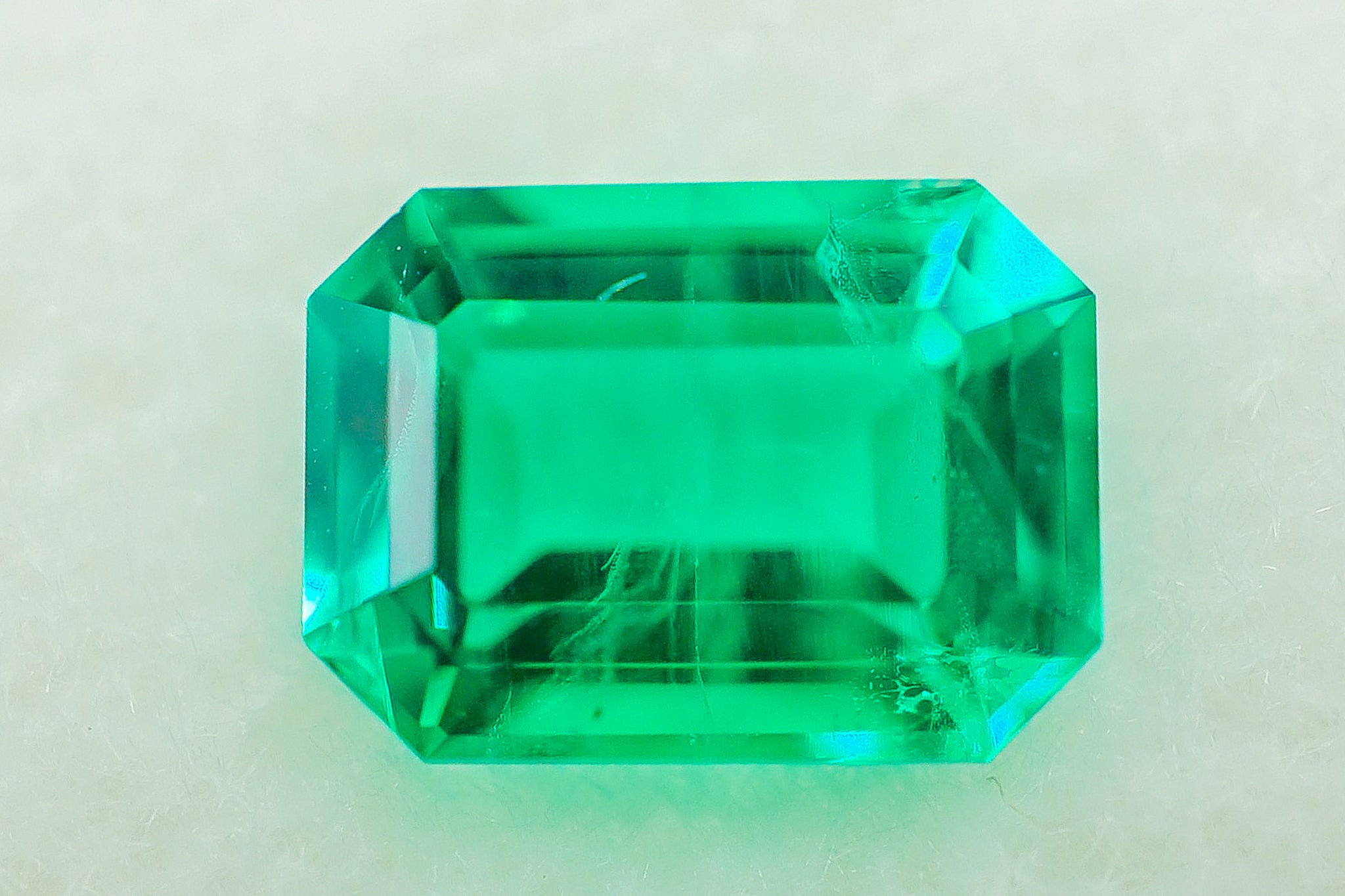 Emerald stone 0.28g emerald-cut rectangular loose green gemstone on light background