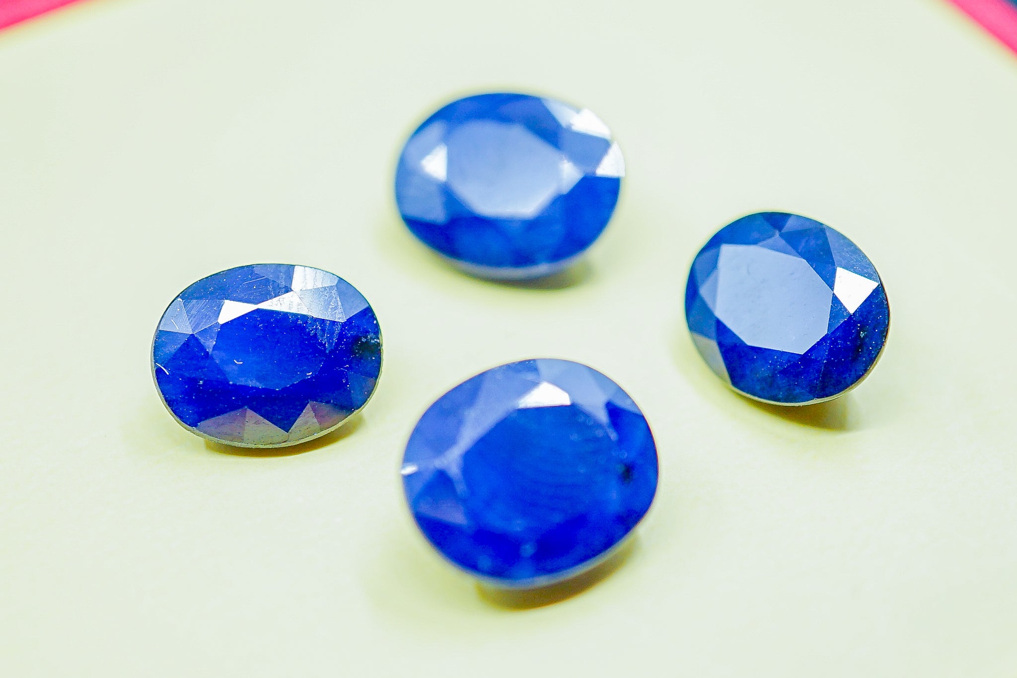 Four faceted blue sapphire gemstones photographed on a light background